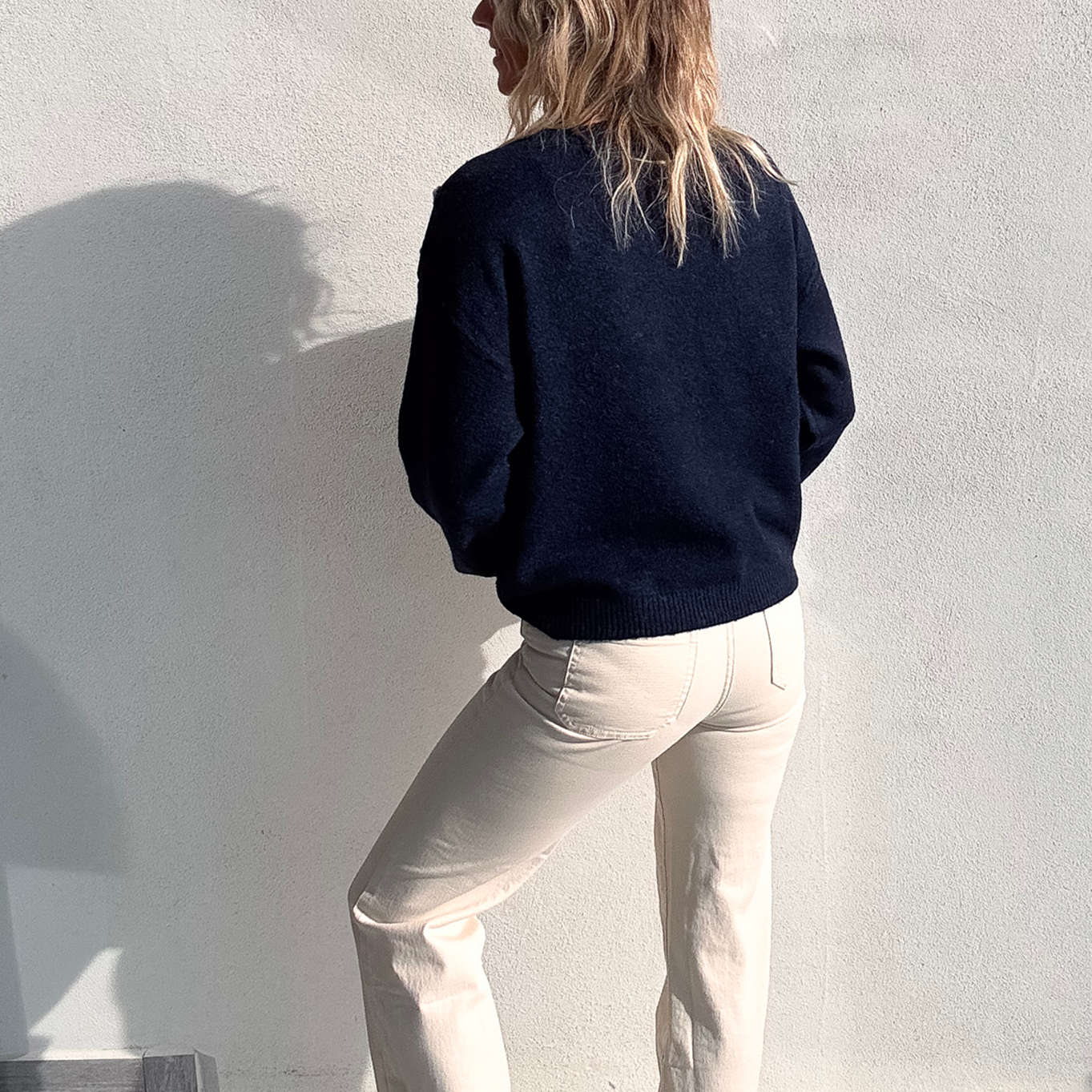 Pull bleu marine avec motif 'amour' cœur fleuri, boutons décoratifs sur l'épaule, porté avec un jean écru et des baskets blanches.