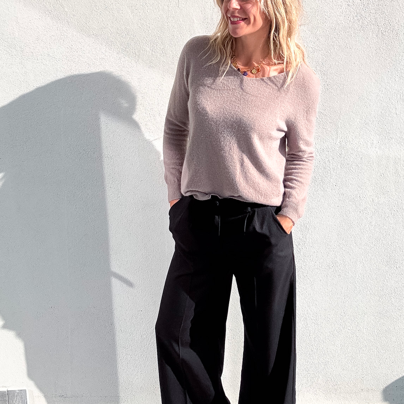 Pantalon large noir taille haute, coupe fluide, porté avec un pull taupe et des baskets blanches, look confortable et élégant.