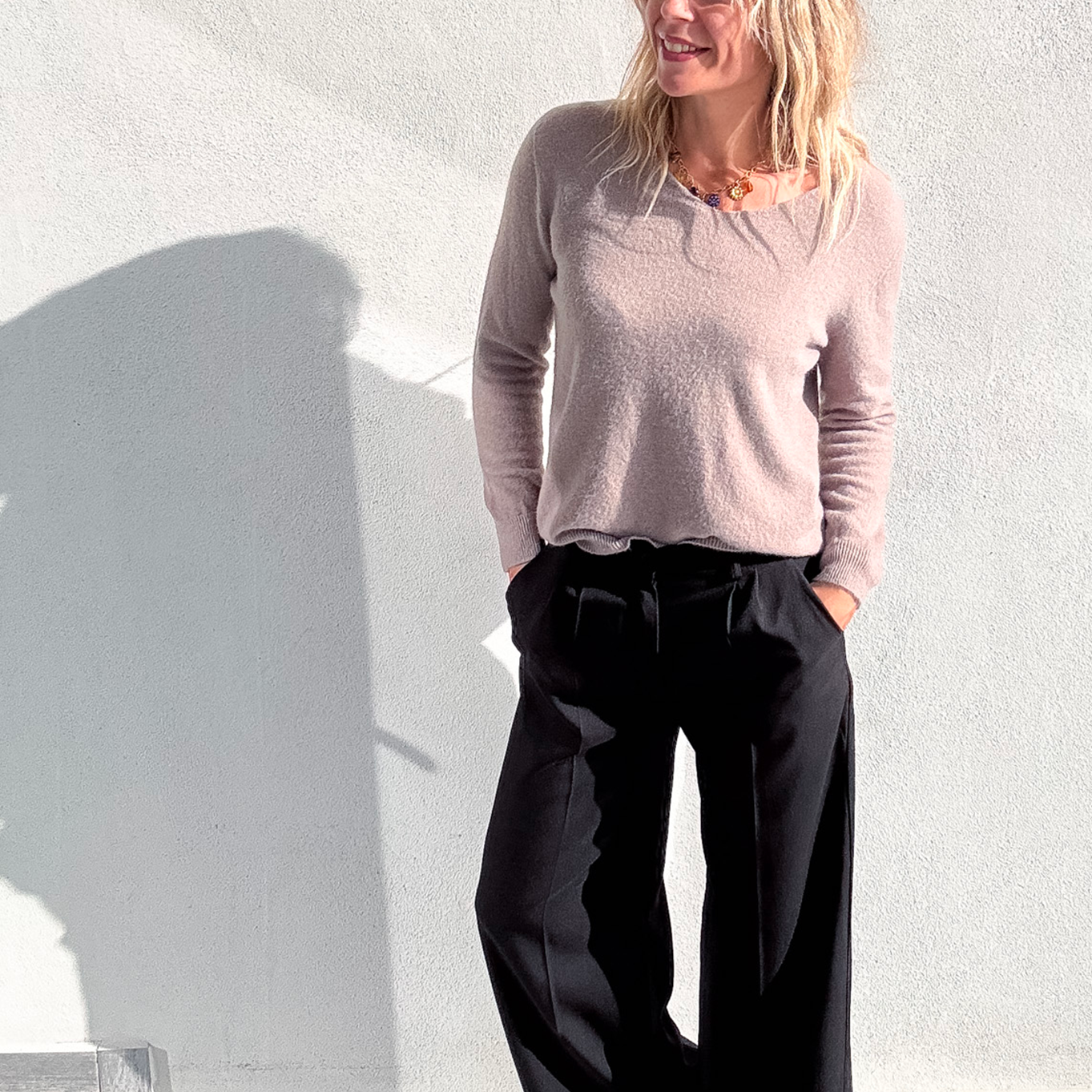 Pantalon large noir taille haute, coupe fluide, porté avec un pull taupe et des baskets blanches, look confortable et élégant.