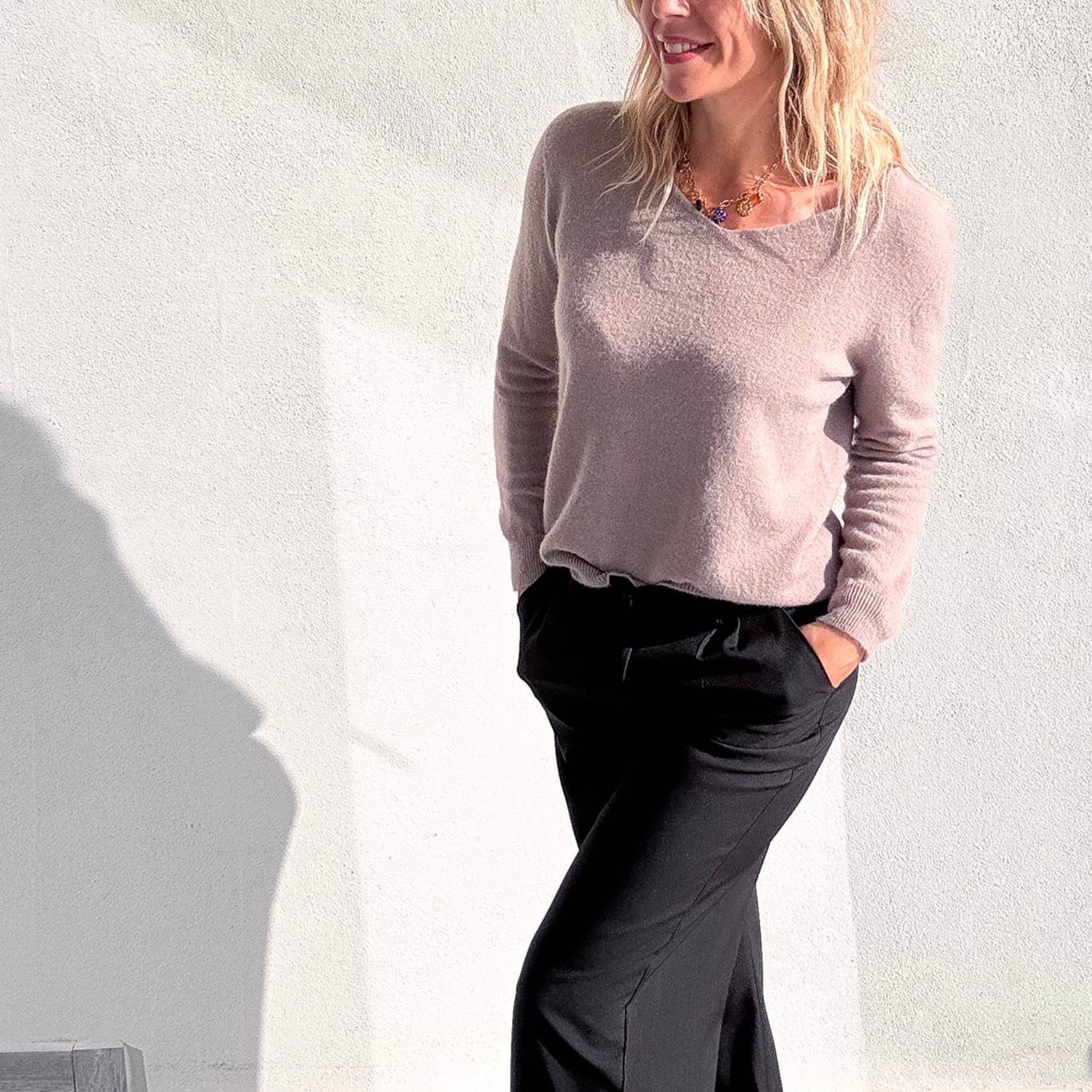 Pantalon large noir taille haute, coupe fluide, porté avec un pull taupe et des baskets blanches, look confortable et élégant.