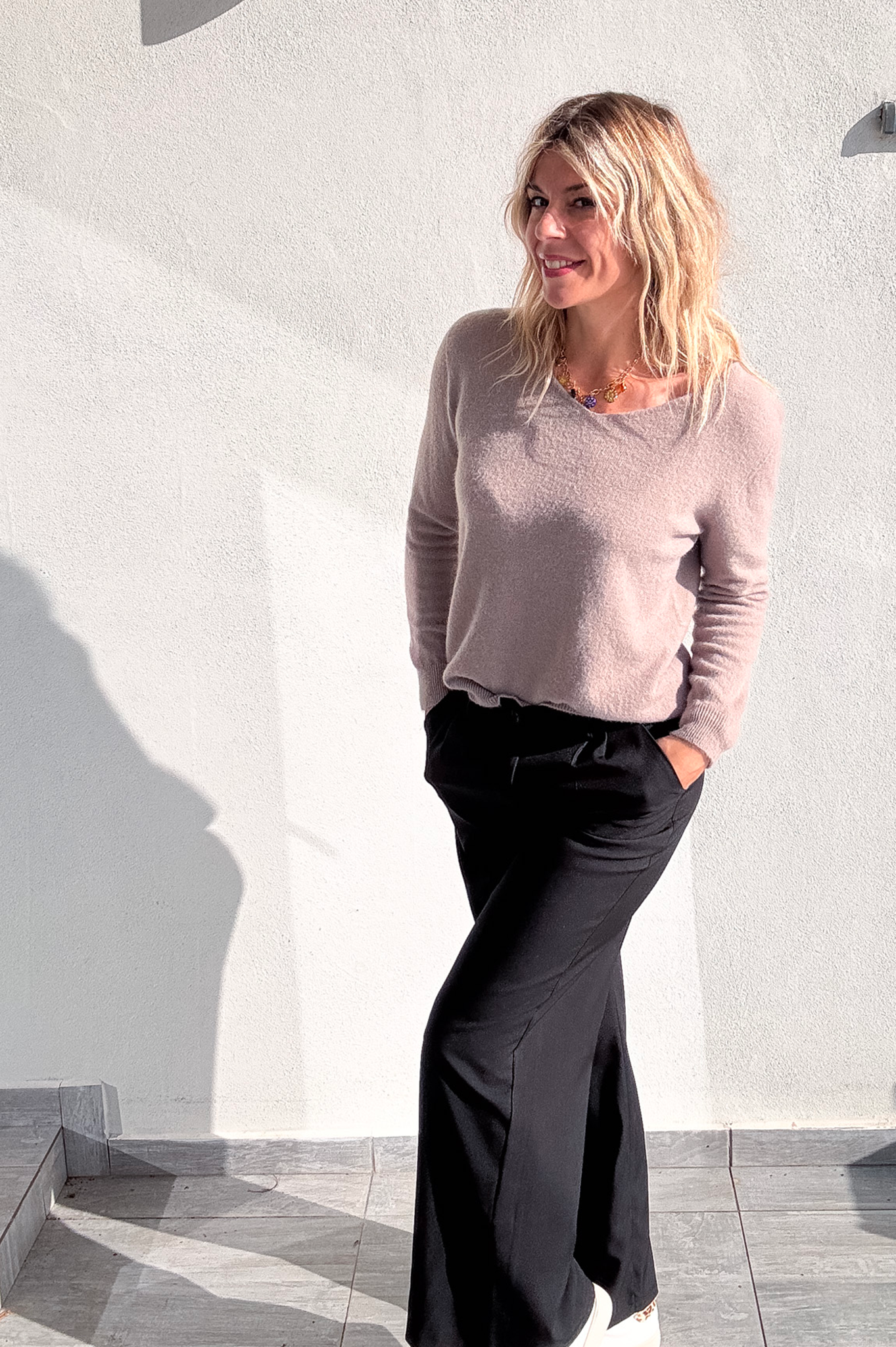 Pantalon large noir taille haute, coupe fluide, porté avec un pull taupe et des baskets blanches, look confortable et élégant.