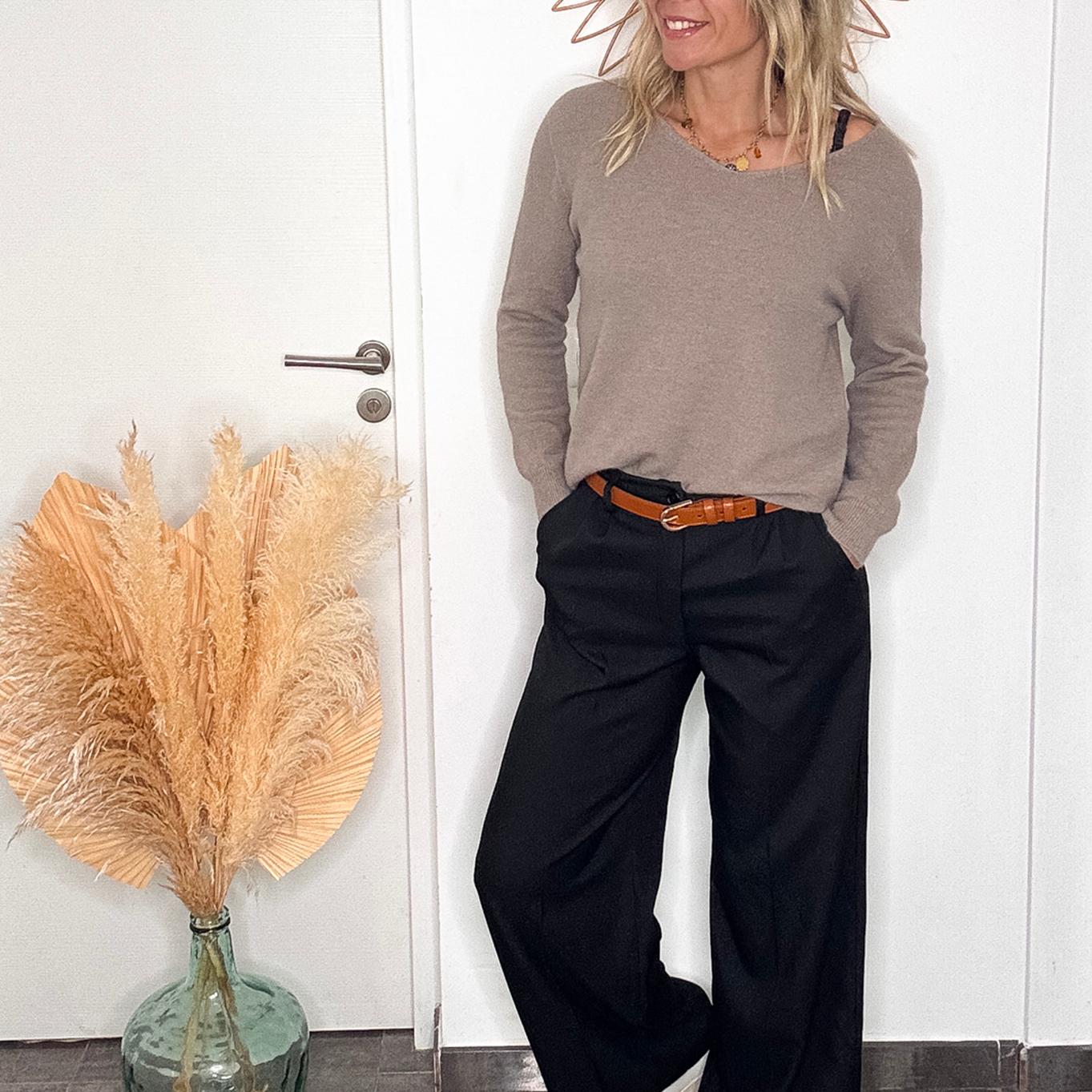 Pantalon large noir taille haute, coupe fluide, porté avec un pull taupe et des baskets blanches, look confortable et élégant.