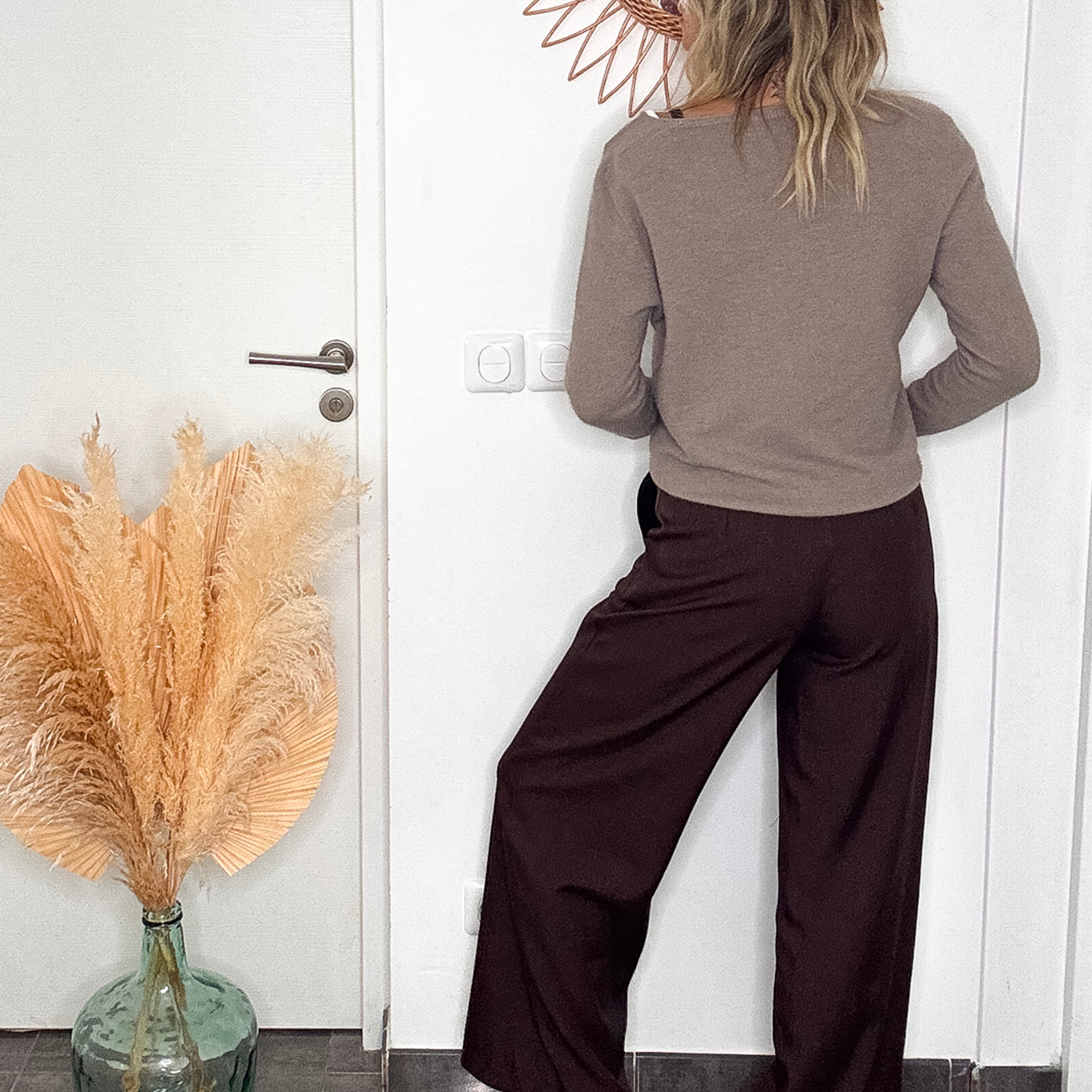 Pantalon tailleur marron chocolat, coupe large taille haute, porté avec un pull taupe, une ceinture camel et des baskets blanches.