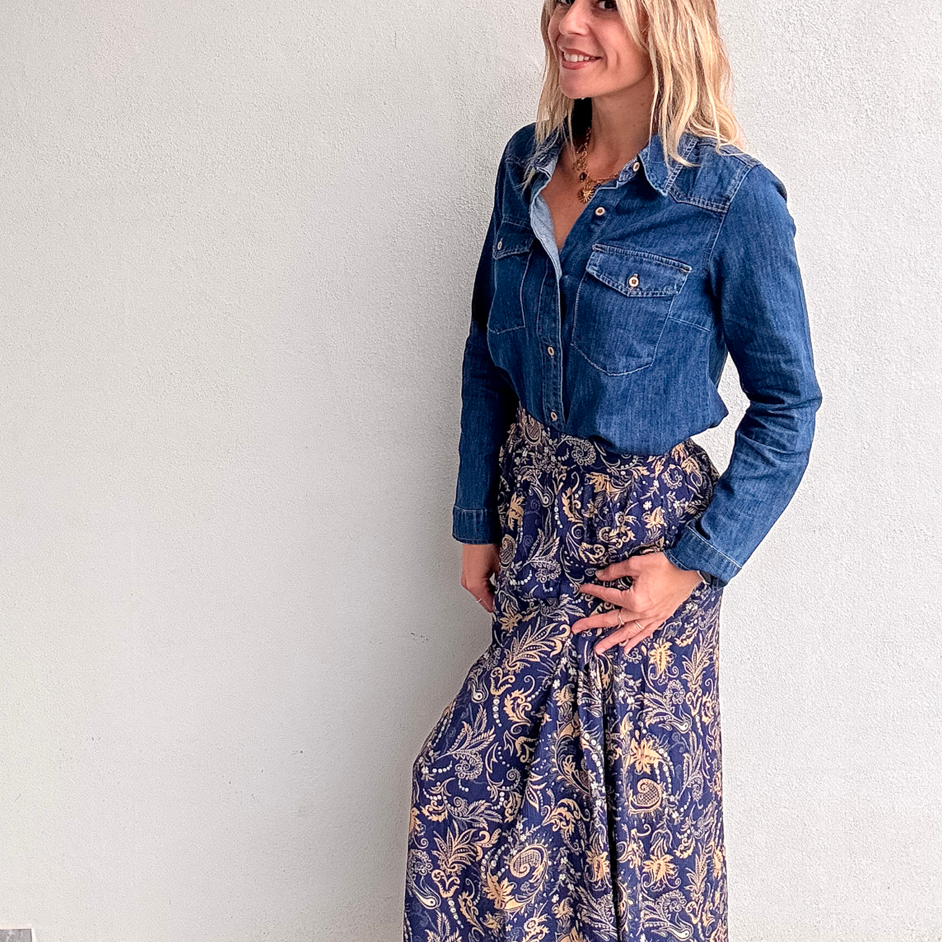 Jupe longue fluide motif cachemire bleu marine et or, portée avec une chemise en jean et des bottines noires.