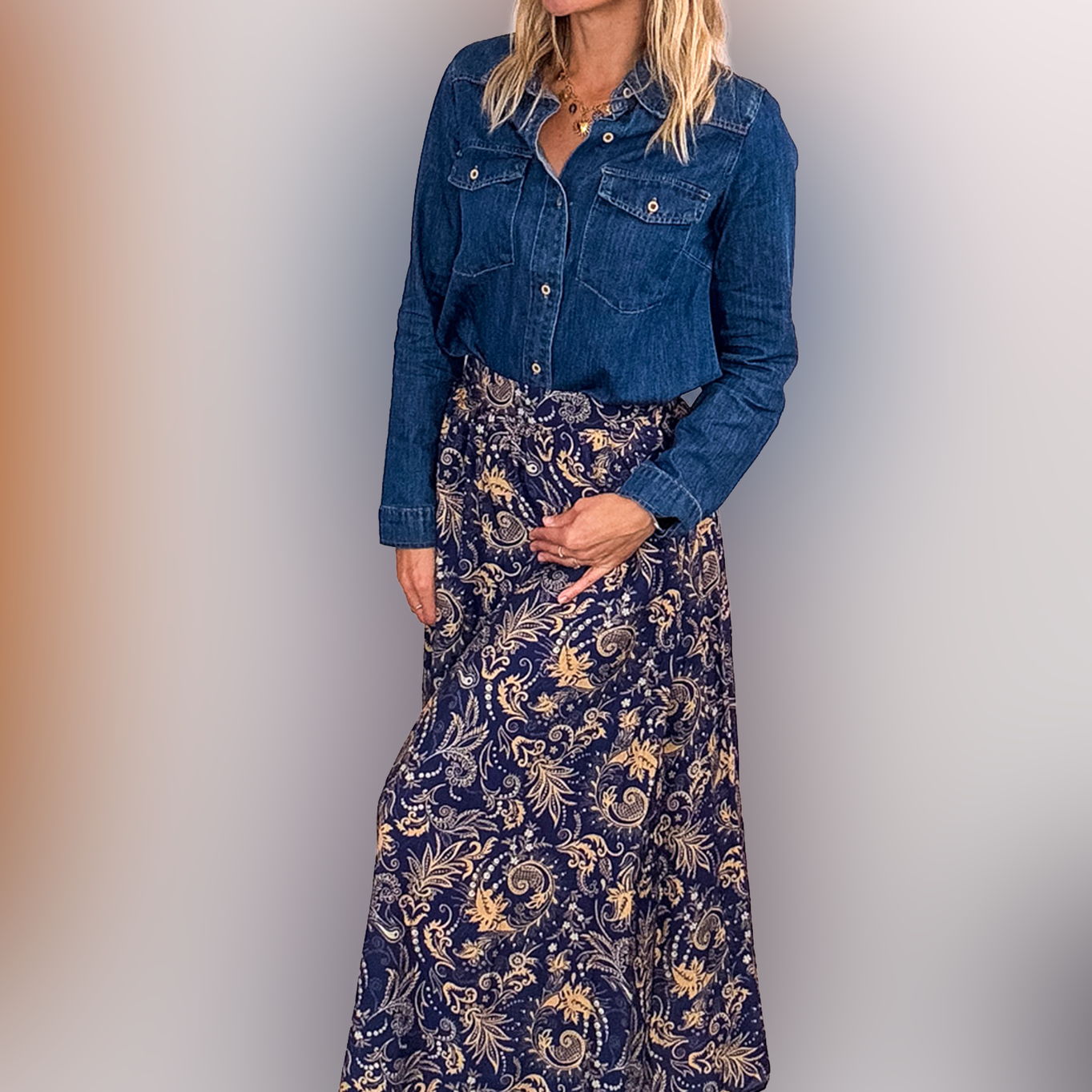 Jupe longue fluide motif cachemire bleu marine et or, portée avec une chemise en jean et des bottines noires.