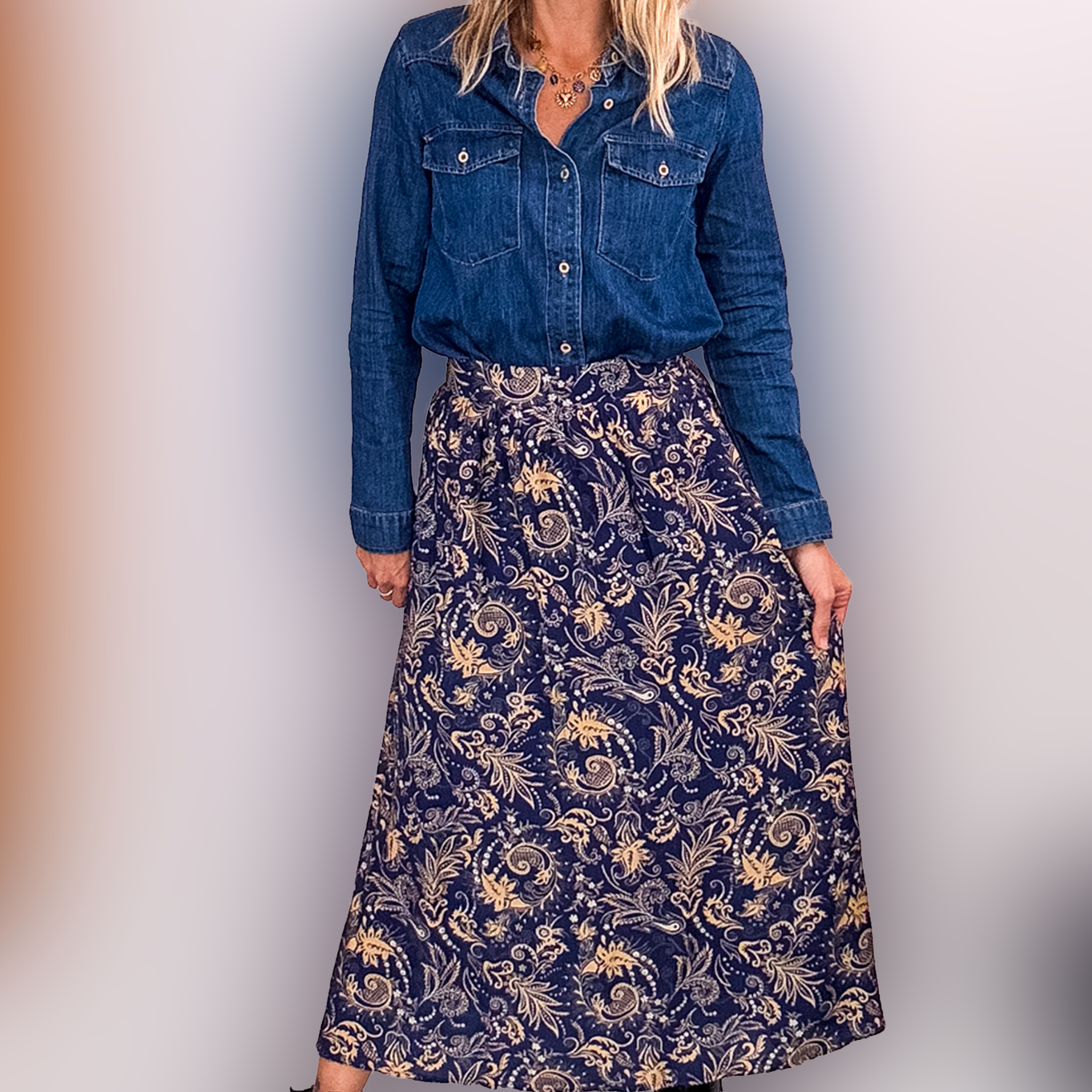 Jupe longue fluide motif cachemire bleu marine et or, portée avec une chemise en jean et des bottines noires.