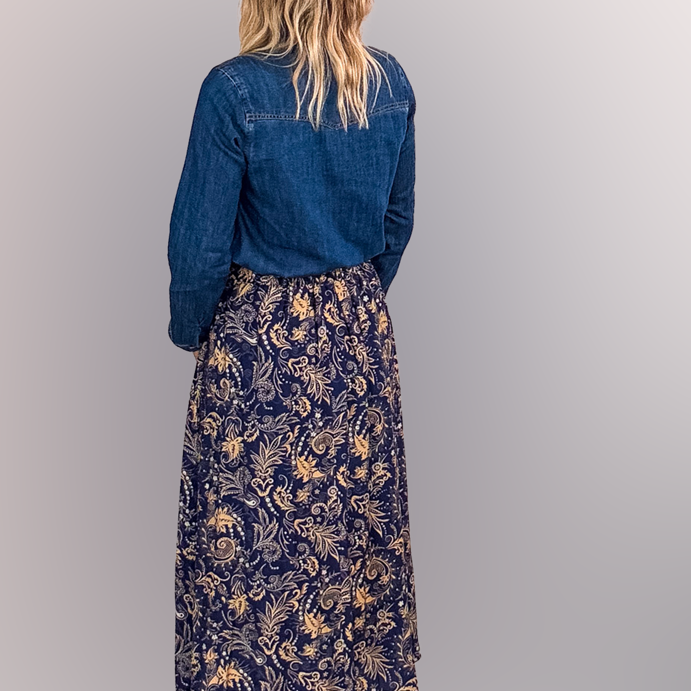 Jupe longue fluide motif cachemire bleu marine et or, portée avec une chemise en jean et des bottines noires.