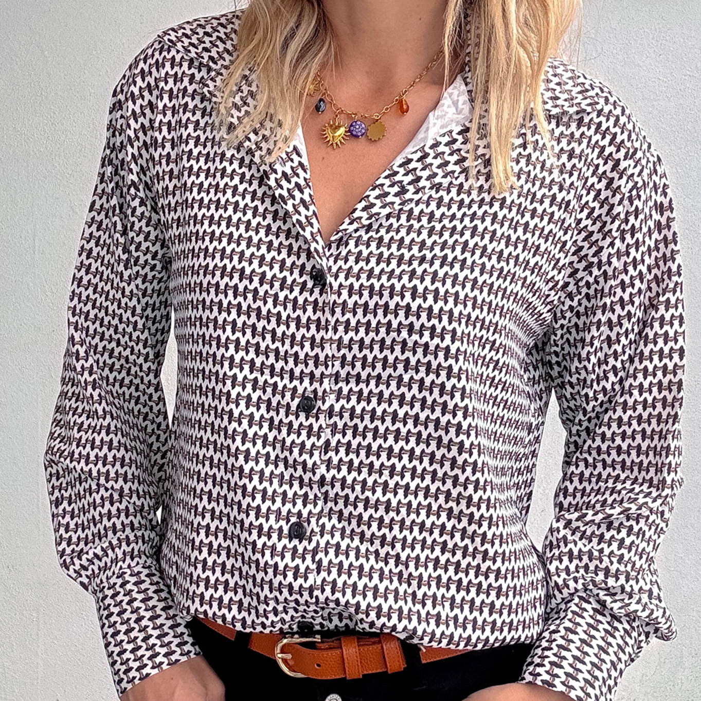 Gros plan Chemise motif pied-de-poule noir et blanc, boutons noirs, et collier multicharmes