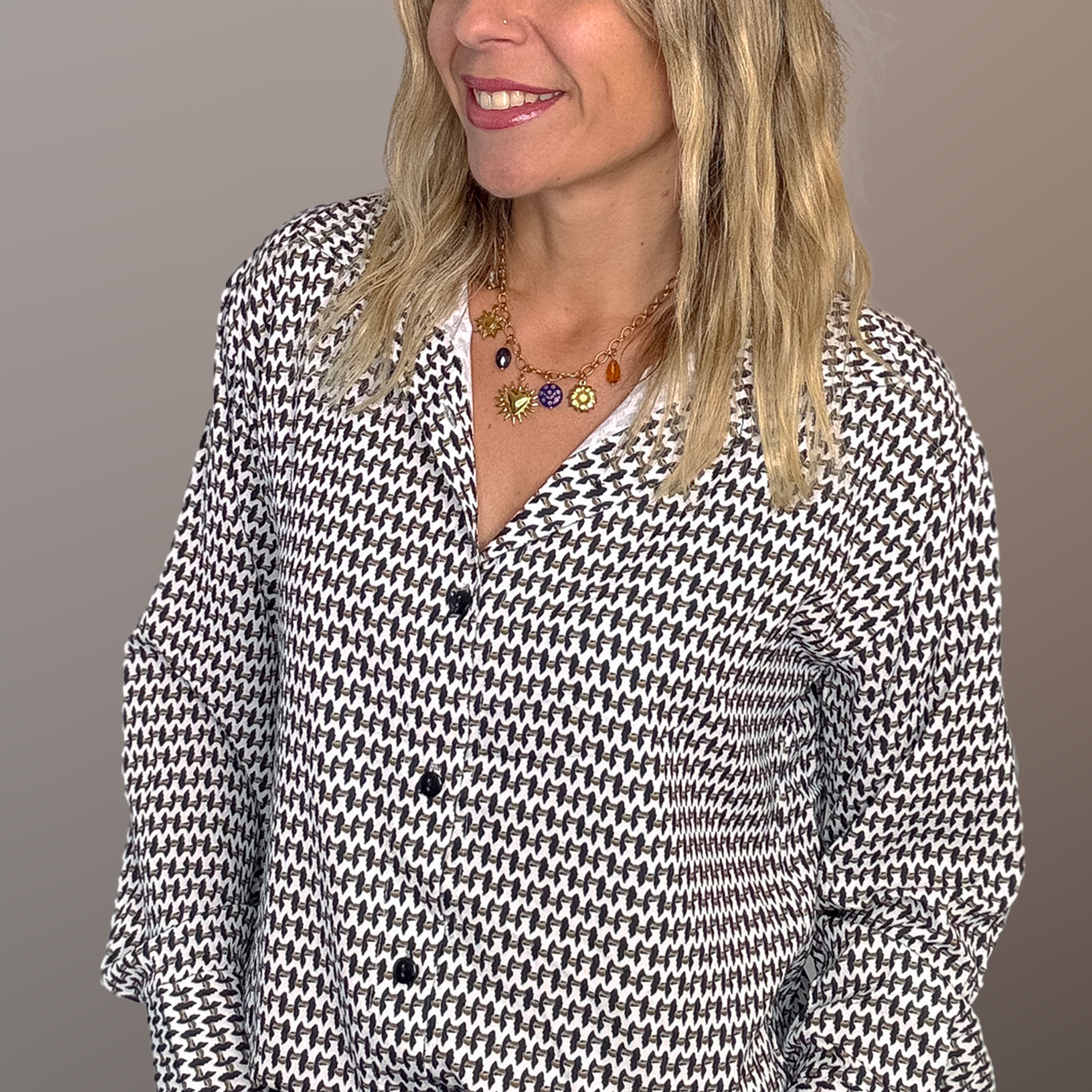 Chemise motif pied-de-poule noir et blanc, boutons noirs, et collier multicharmes