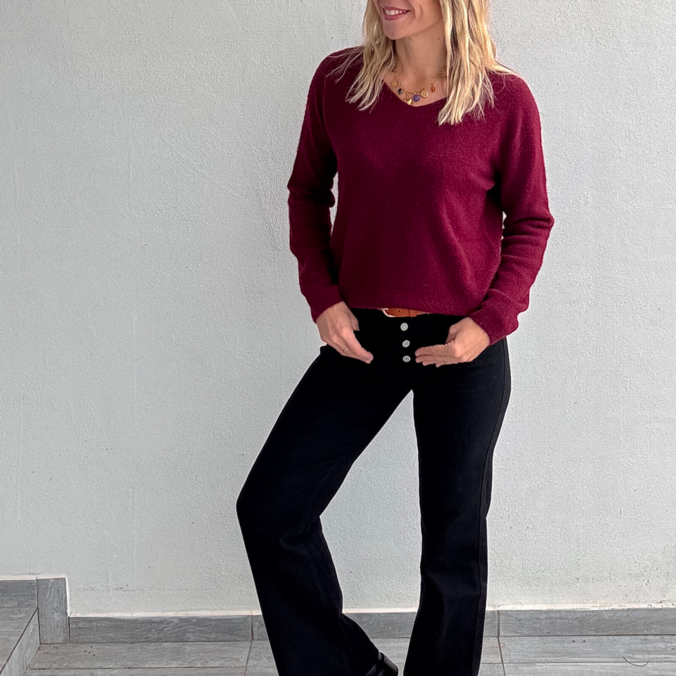 Pull bordeaux col V en maille douce, Taille Unique, porté rentré dans un jean noir taille haute avec une ceinture camel