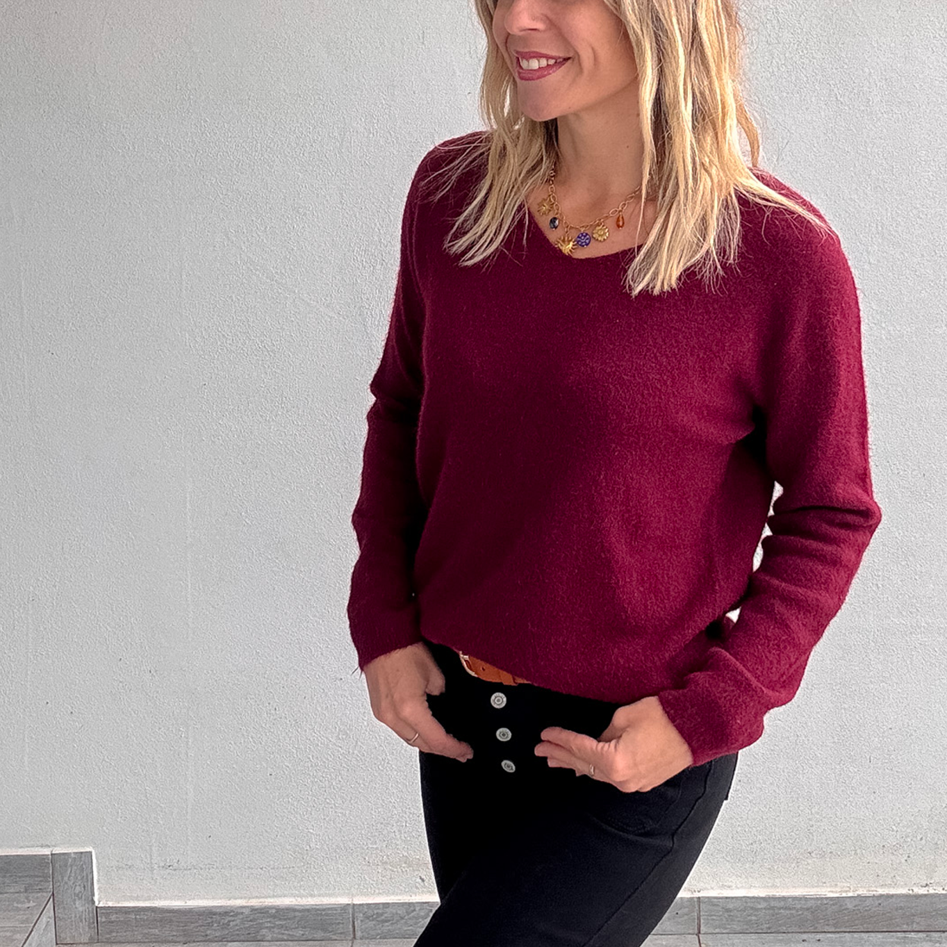 Pull bordeaux col V en maille douce, Taille Unique, porté rentré dans un jean noir taille haute avec une ceinture camel