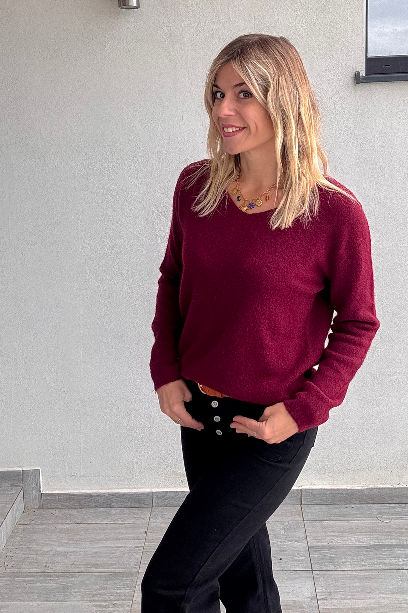 Pull bordeaux col V en maille douce, Taille Unique, porté rentré dans un jean noir taille haute avec une ceinture camel