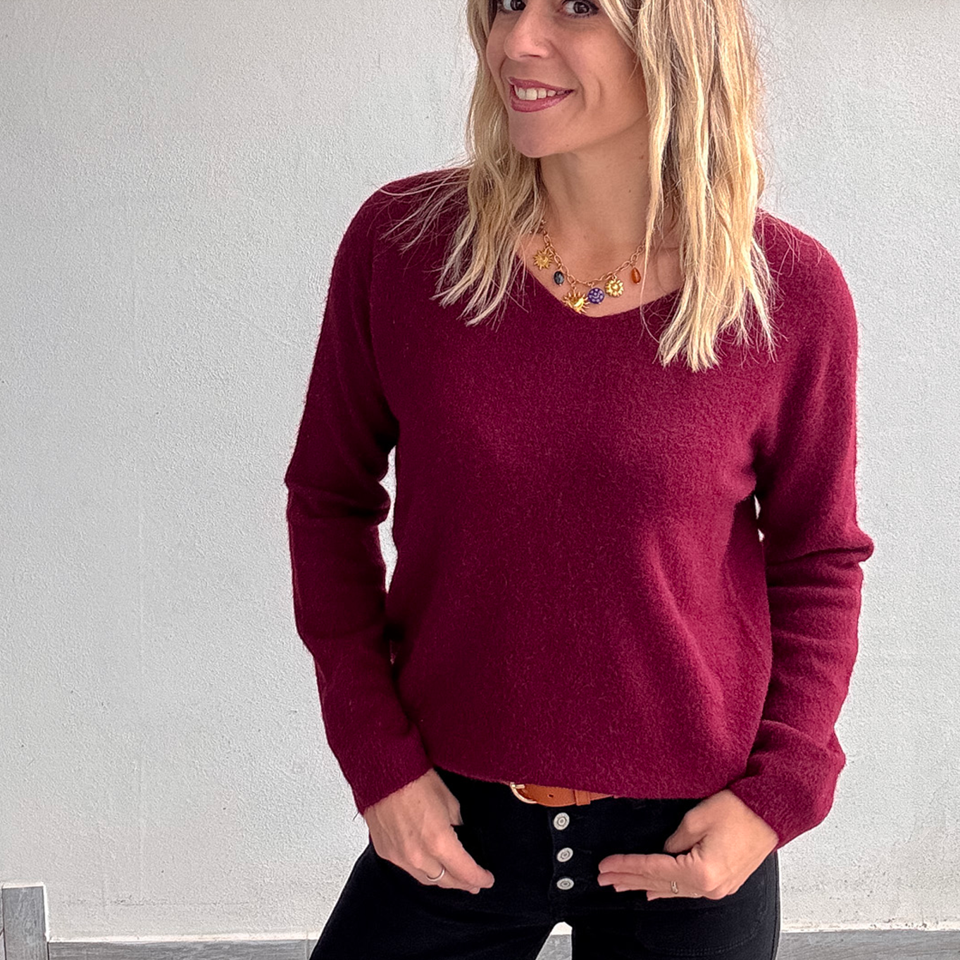 Pull bordeaux col V en maille douce, Taille Unique, porté rentré dans un jean noir taille haute avec une ceinture camel