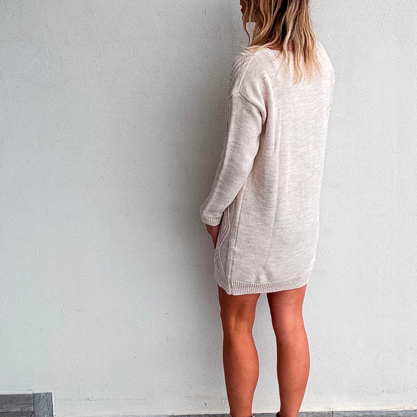 Robe pull courte torsadée couleur écru, portée avec des bottines claires, style d'hiver chic