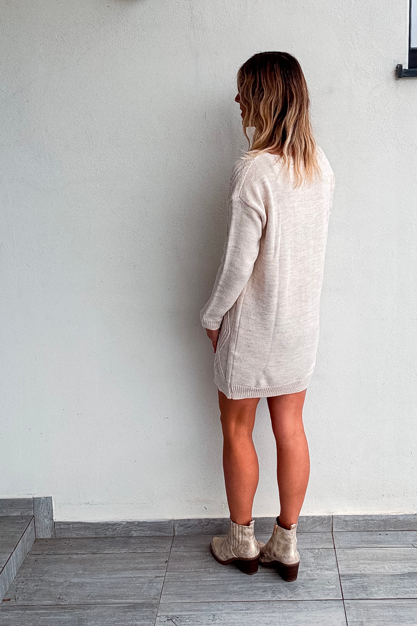 Robe pull courte torsadée couleur écru, portée avec des bottines claires, style d'hiver chic