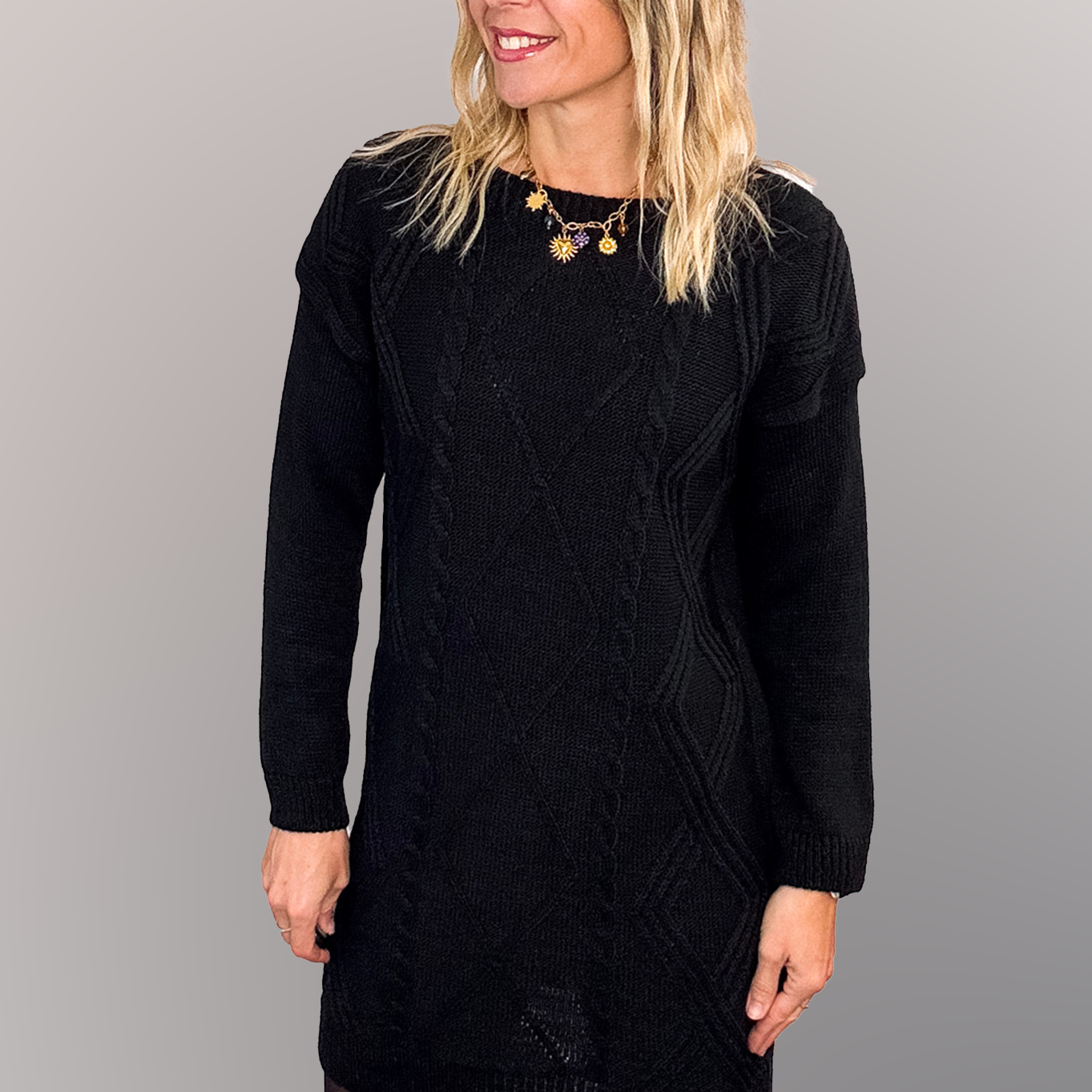 Robe pull courte noire en maille torsadée, des collants noirs et des bottines.