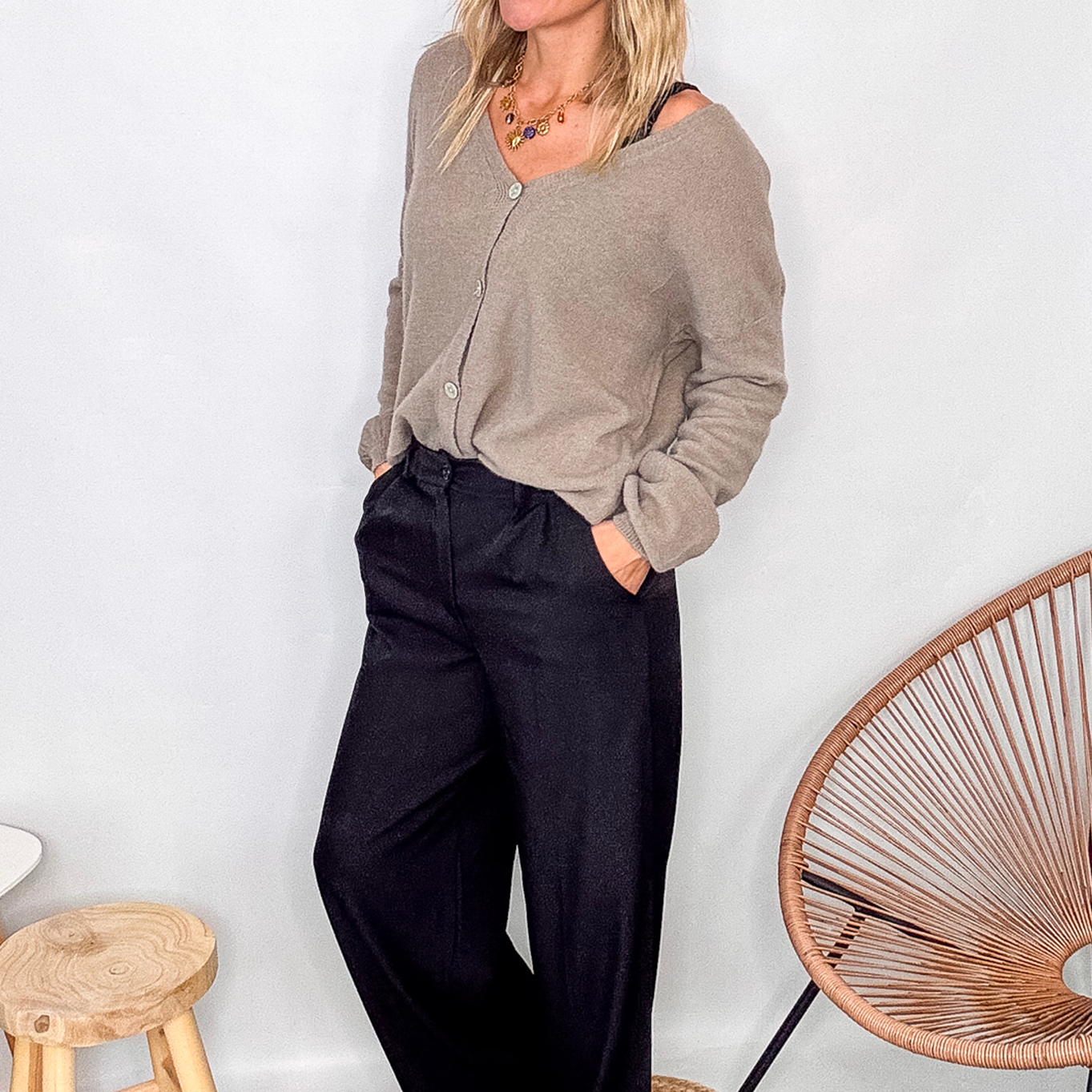 Gilet cardigan taupe maille fine porté rentré dans un pantalon large noir, look chic et confortable.