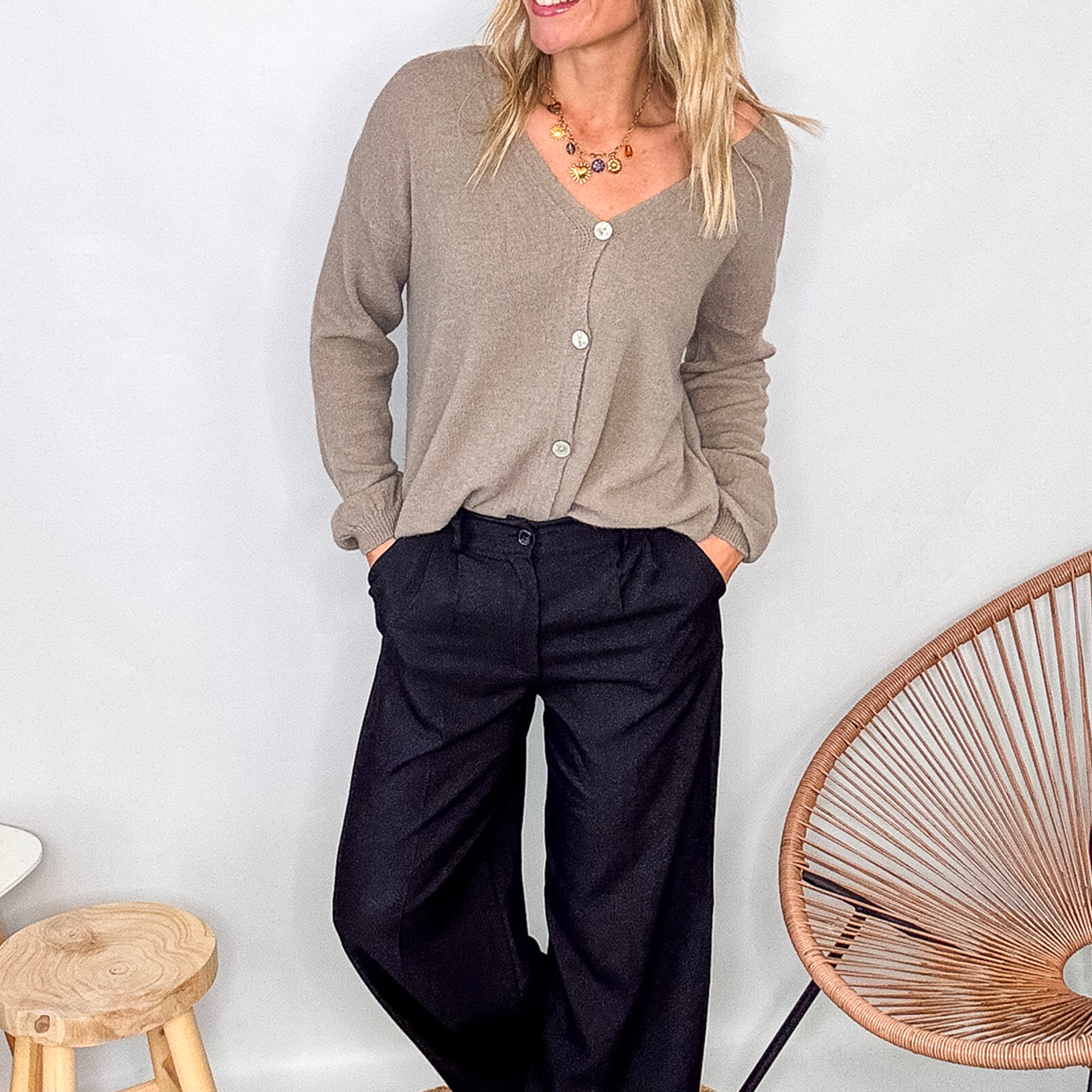 Gilet cardigan taupe maille fine porté rentré dans un pantalon large noir, look chic et confortable.