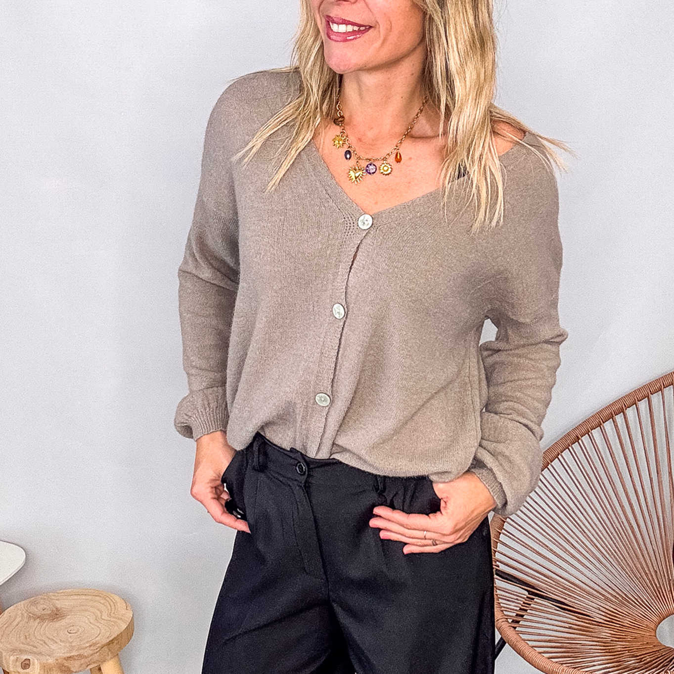 Gilet cardigan taupe maille fine porté rentré dans un pantalon large noir, look chic et confortable.