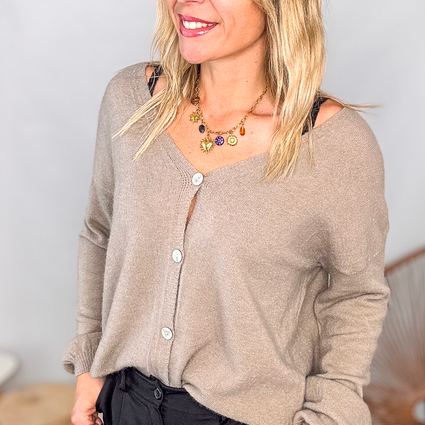 Gilet cardigan taupe maille fine porté rentré dans un pantalon large noir, look chic et confortable.