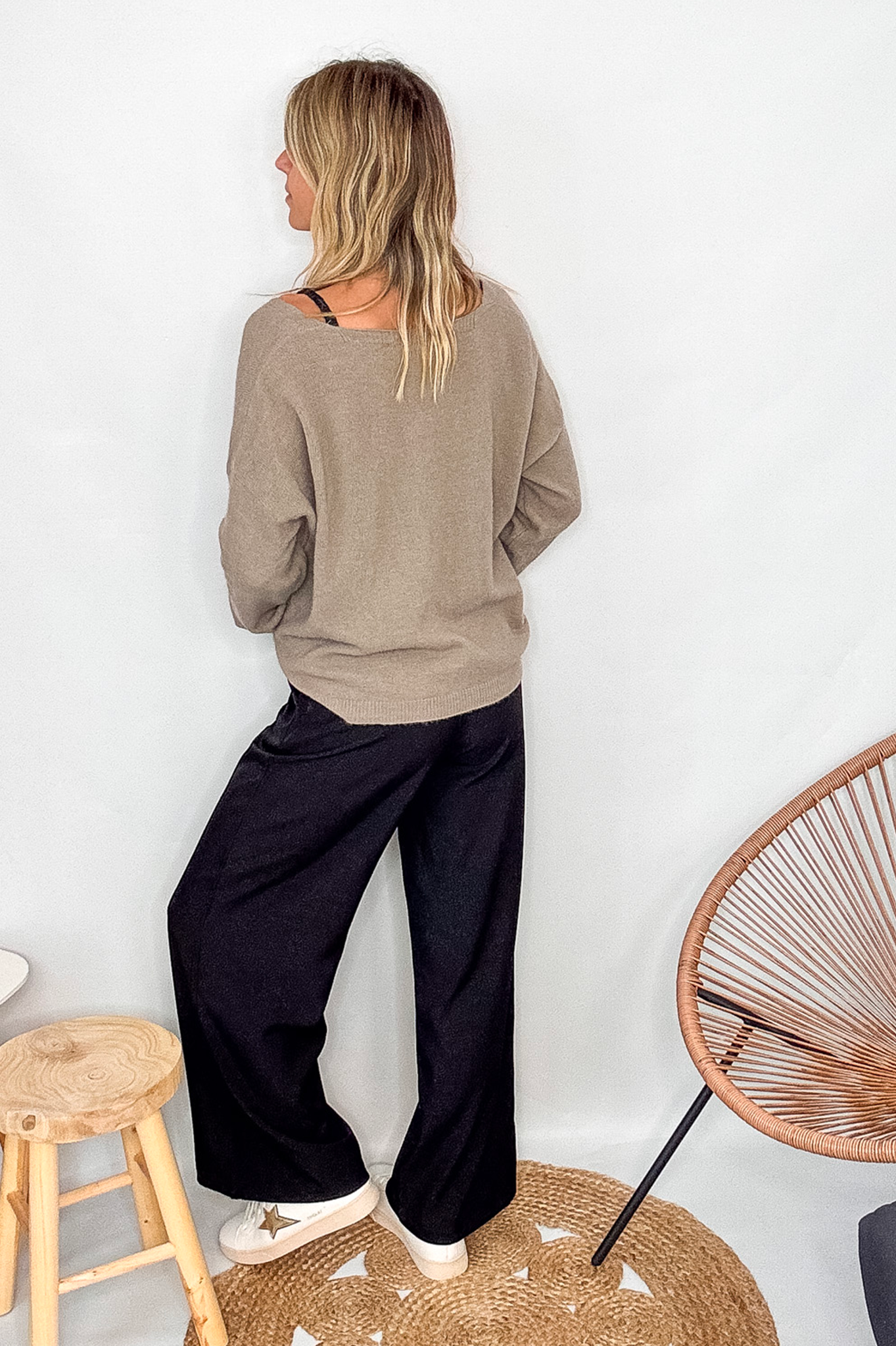 Gilet cardigan taupe maille fine porté rentré dans un pantalon large noir, look chic et confortable.