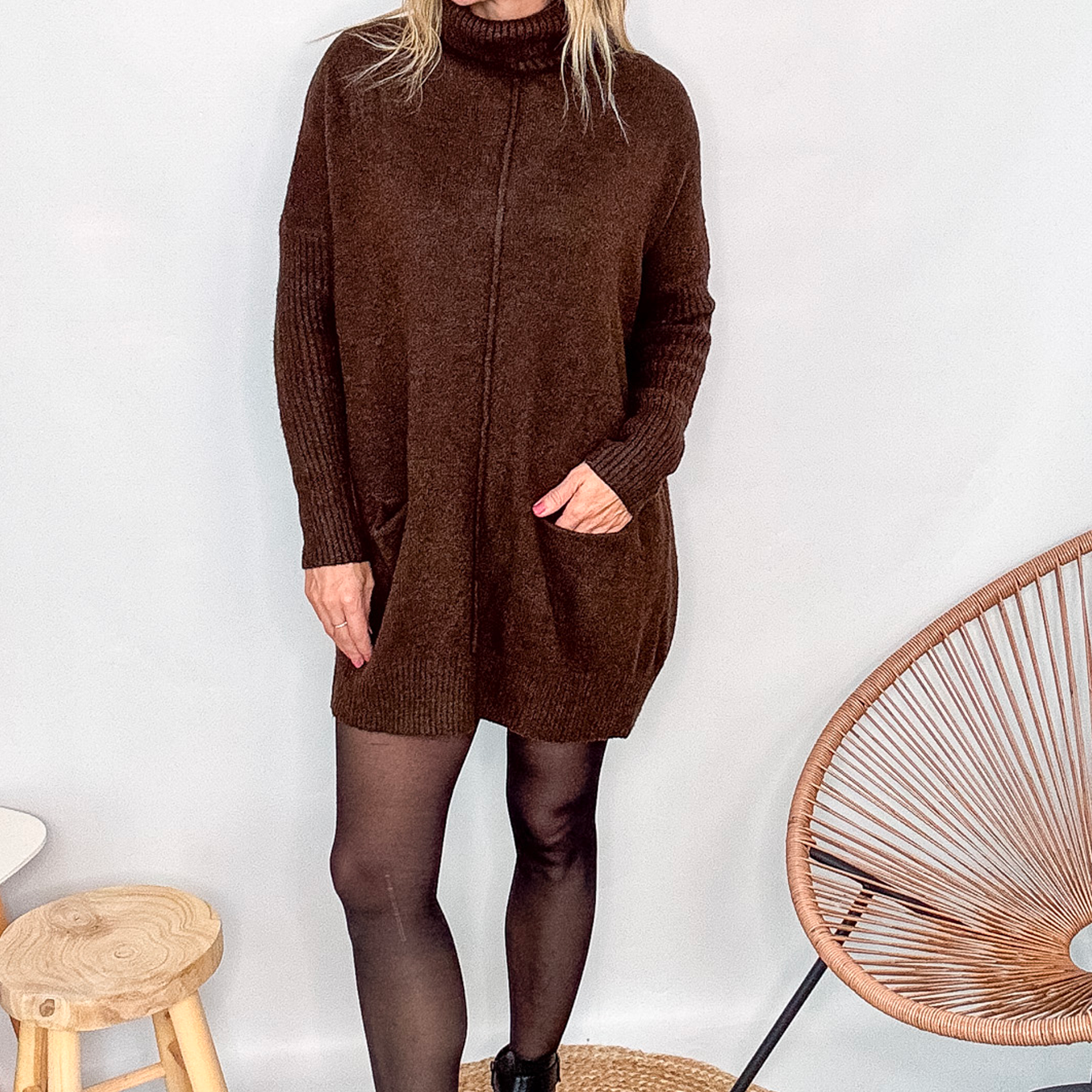 Robe pull marron chocolat col roulé avec poches, coupe ample, portée avec des collants noirs et des bottines.