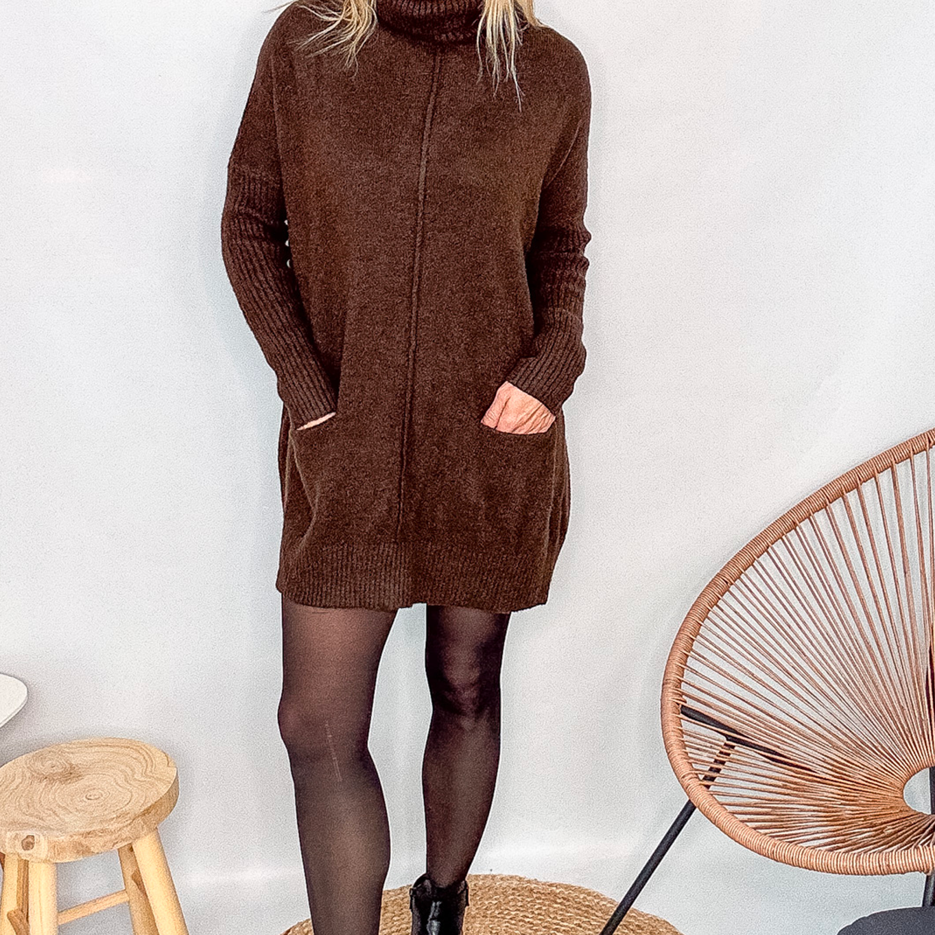 Robe pull marron chocolat col roulé avec poches, coupe ample, portée avec des collants noirs et des bottines.