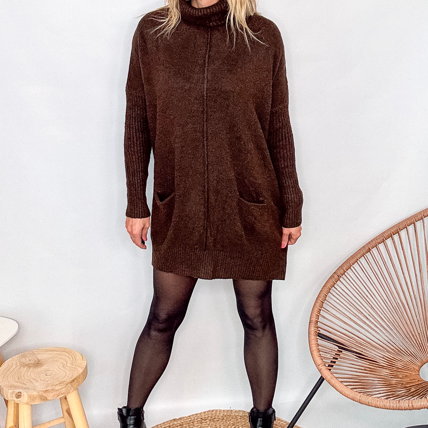 Robe pull marron chocolat col roulé avec poches, coupe ample, portée avec des collants noirs et des bottines.