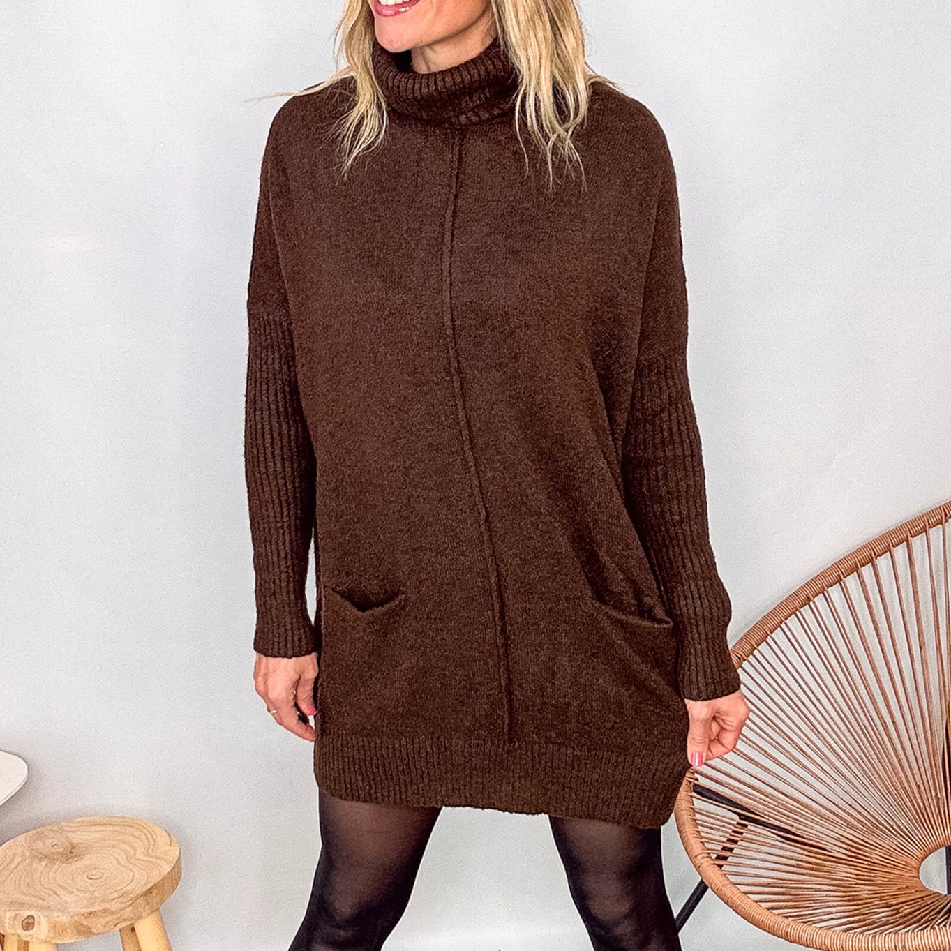 Robe pull marron chocolat col roulé avec poches, coupe ample, portée avec des collants noirs et des bottines.