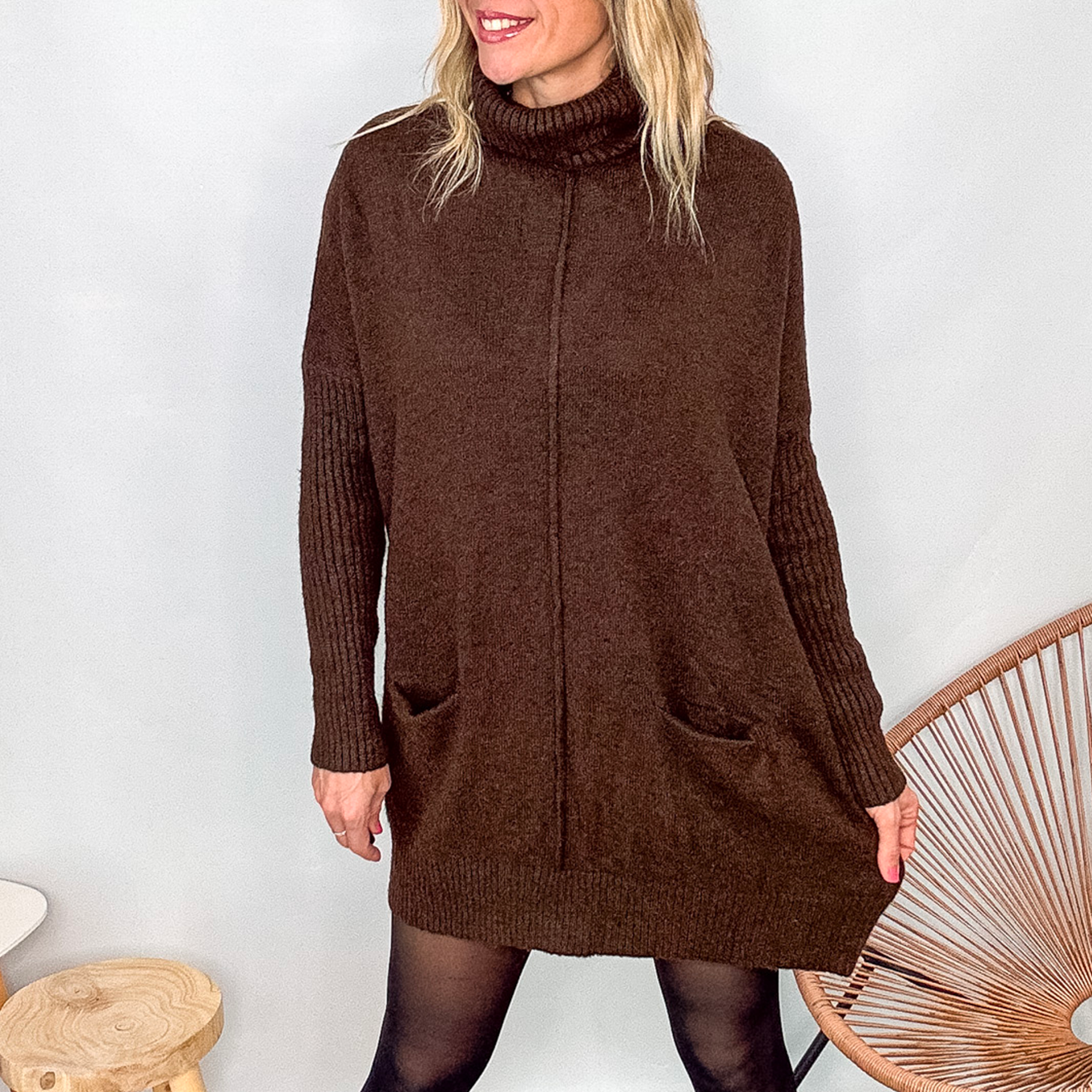 Robe pull marron chocolat col roulé avec poches, coupe ample, portée avec des collants noirs et des bottines.