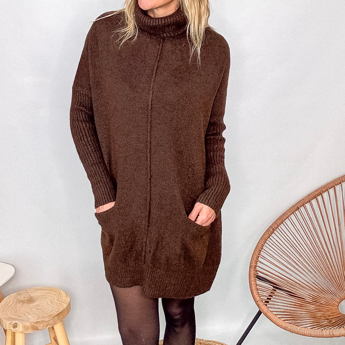 Robe pull marron chocolat col roulé avec poches, coupe ample, portée avec des collants noirs et des bottines.