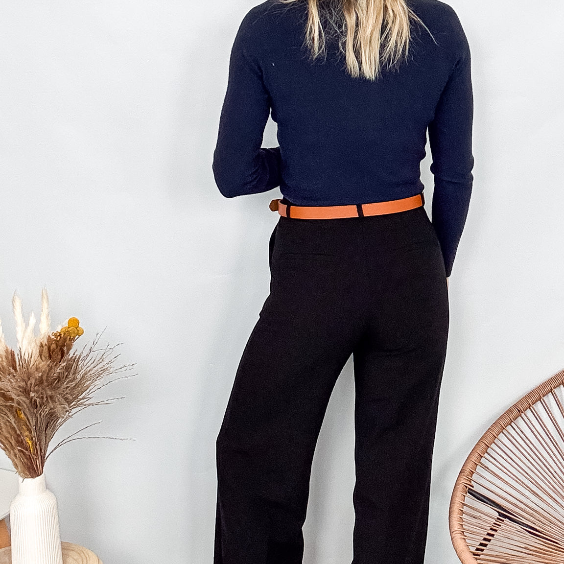Pantalon tailleur noir fluide, coupe droite, porté avec un pull bordeaux et des accessoires.