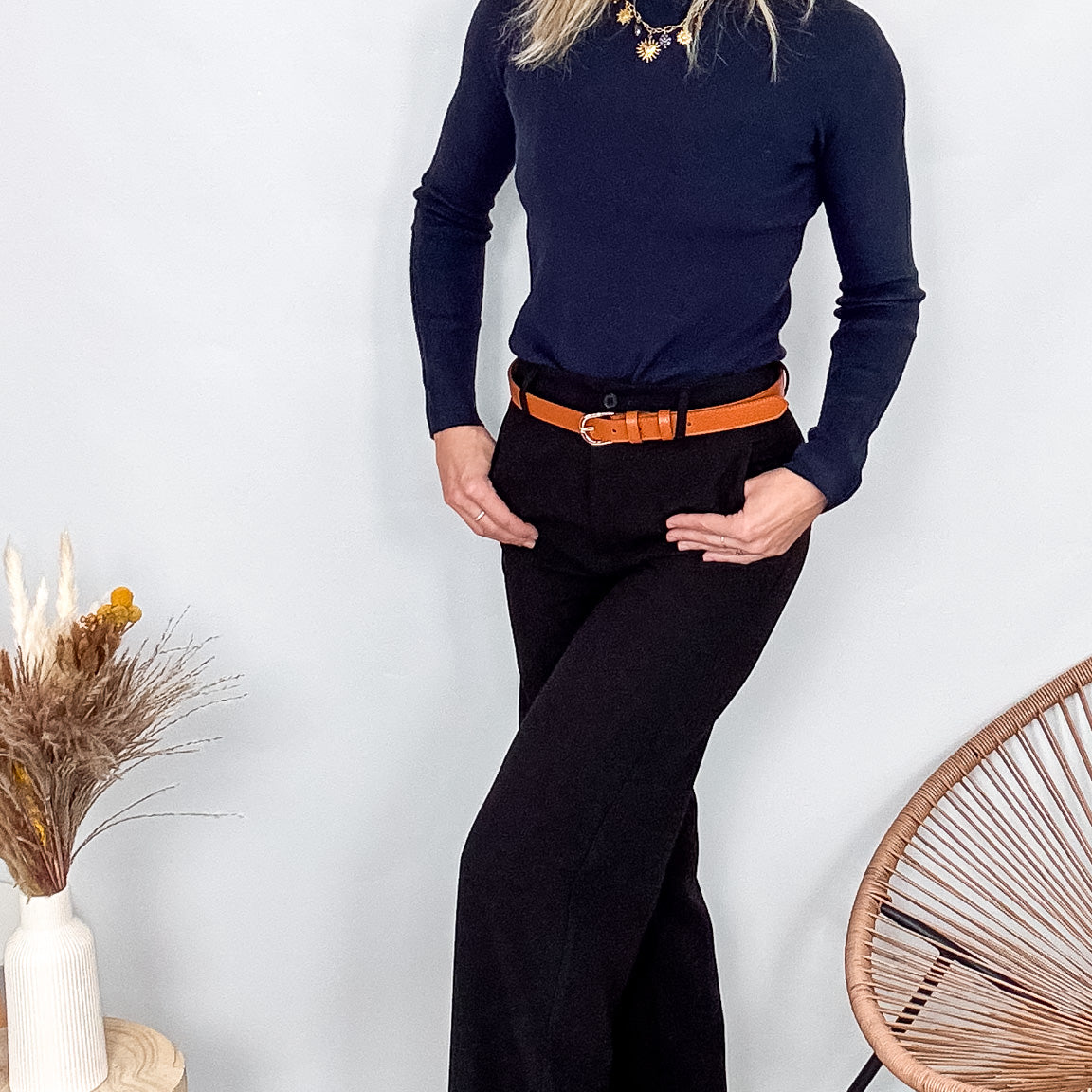 Pantalon tailleur noir fluide, coupe droite, porté avec un pull bordeaux et des accessoires.