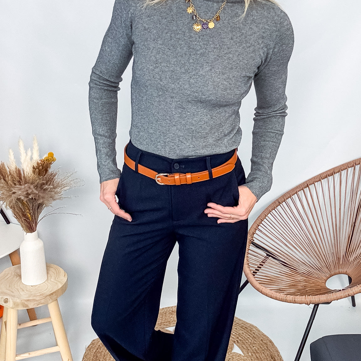 Pull fin gris foncé col rond en maille douce, porté rentré dans un jean noir taille haute avec une ceinture.