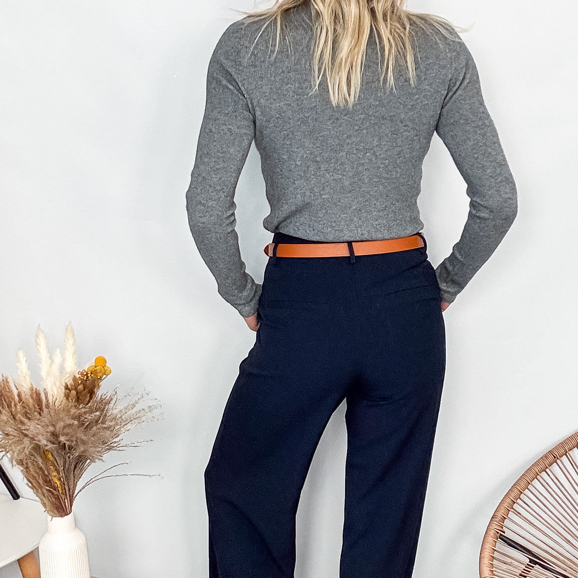 Pull fin gris foncé col rond en maille douce, porté rentré dans un jean noir taille haute avec une ceinture.