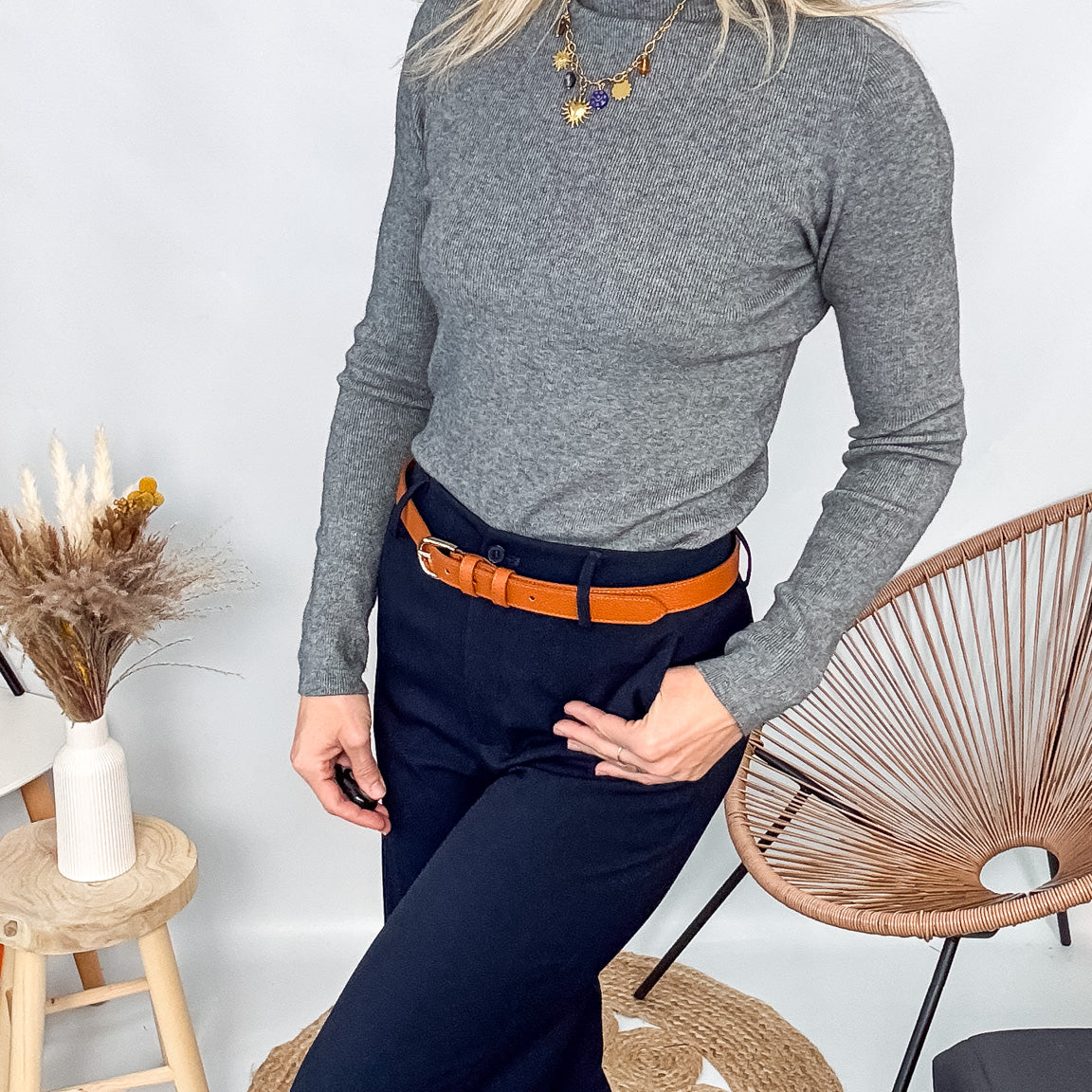 Pull fin gris foncé col rond en maille douce, porté rentré dans un jean noir taille haute avec une ceinture.