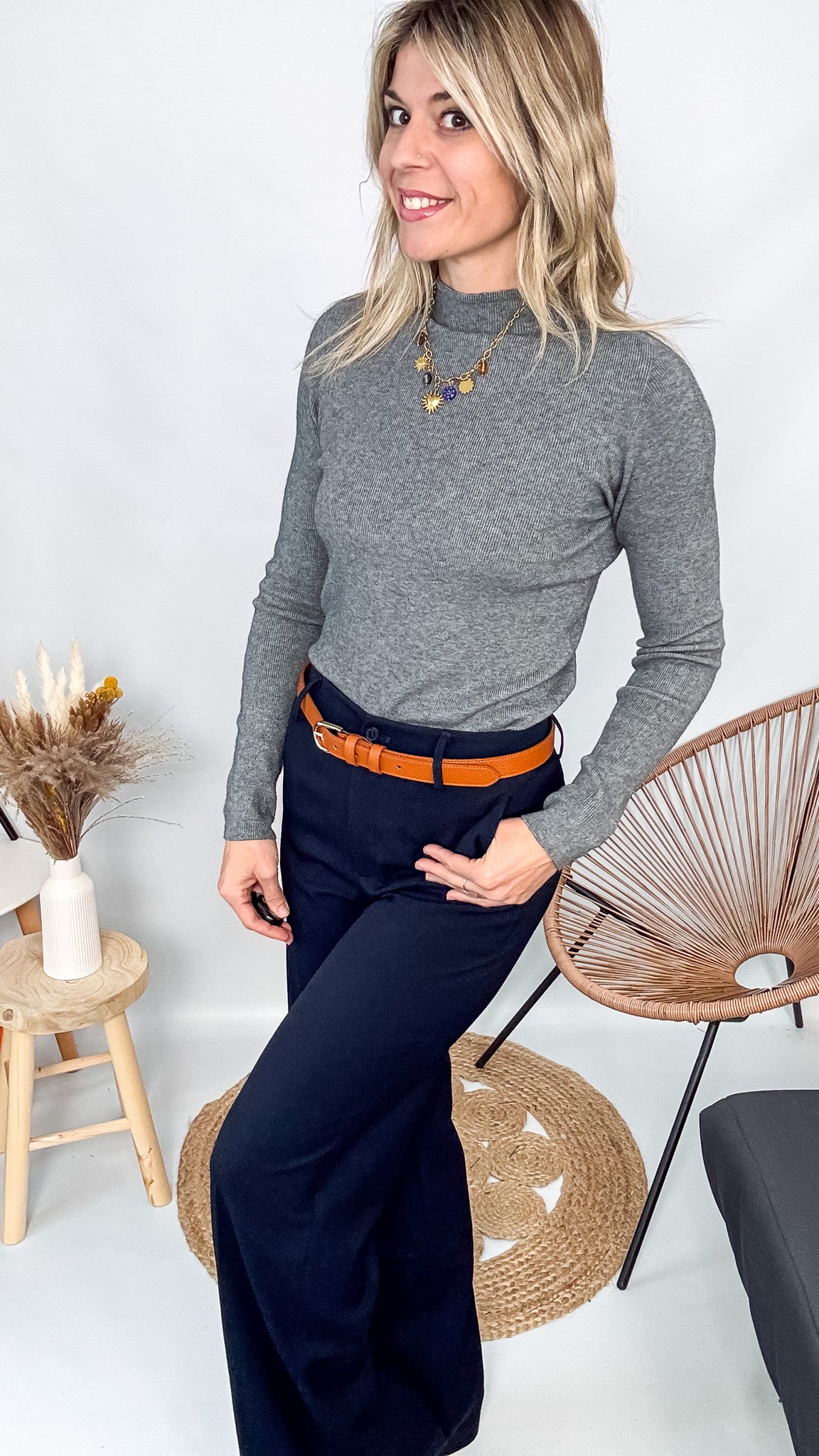 Pull fin gris foncé col rond en maille douce, porté rentré dans un jean noir taille haute avec une ceinture.