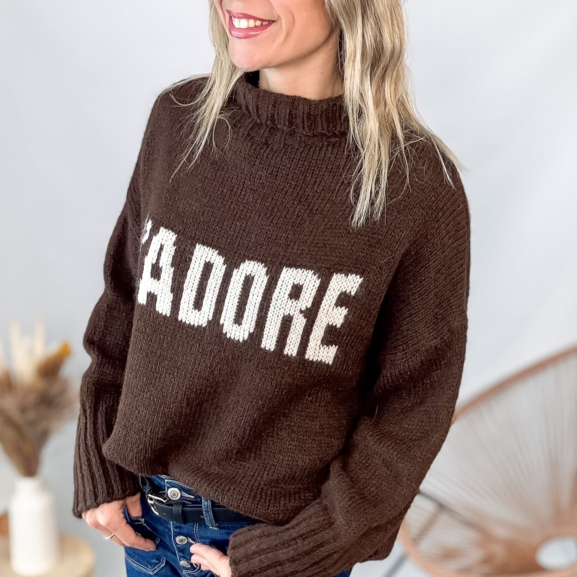 Pull marron col roulé maille, fabriqué en Italie, porté rentré dans un pantalon foncé.