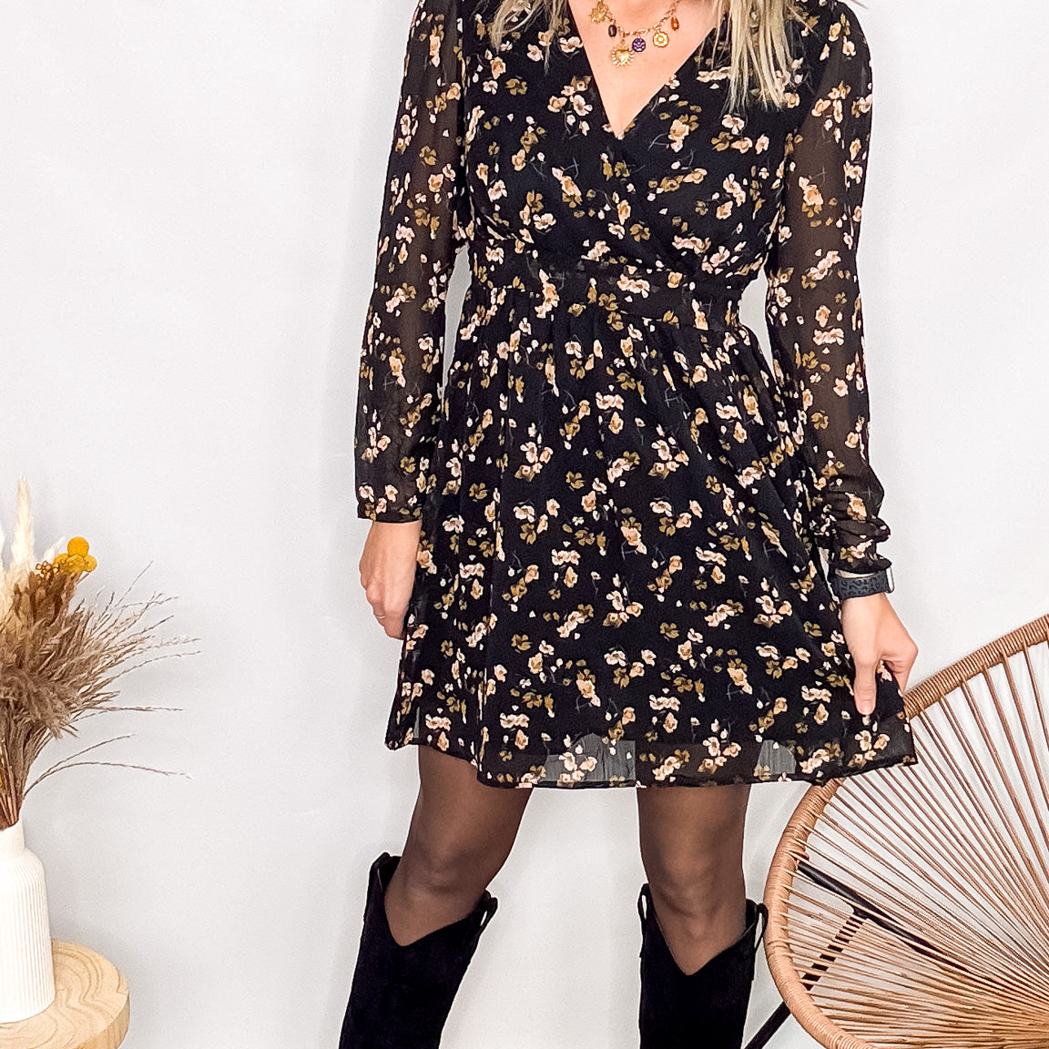 Robe noire fleurie 100% polyester, coupe fluide, portée avec des collants et des bottines.