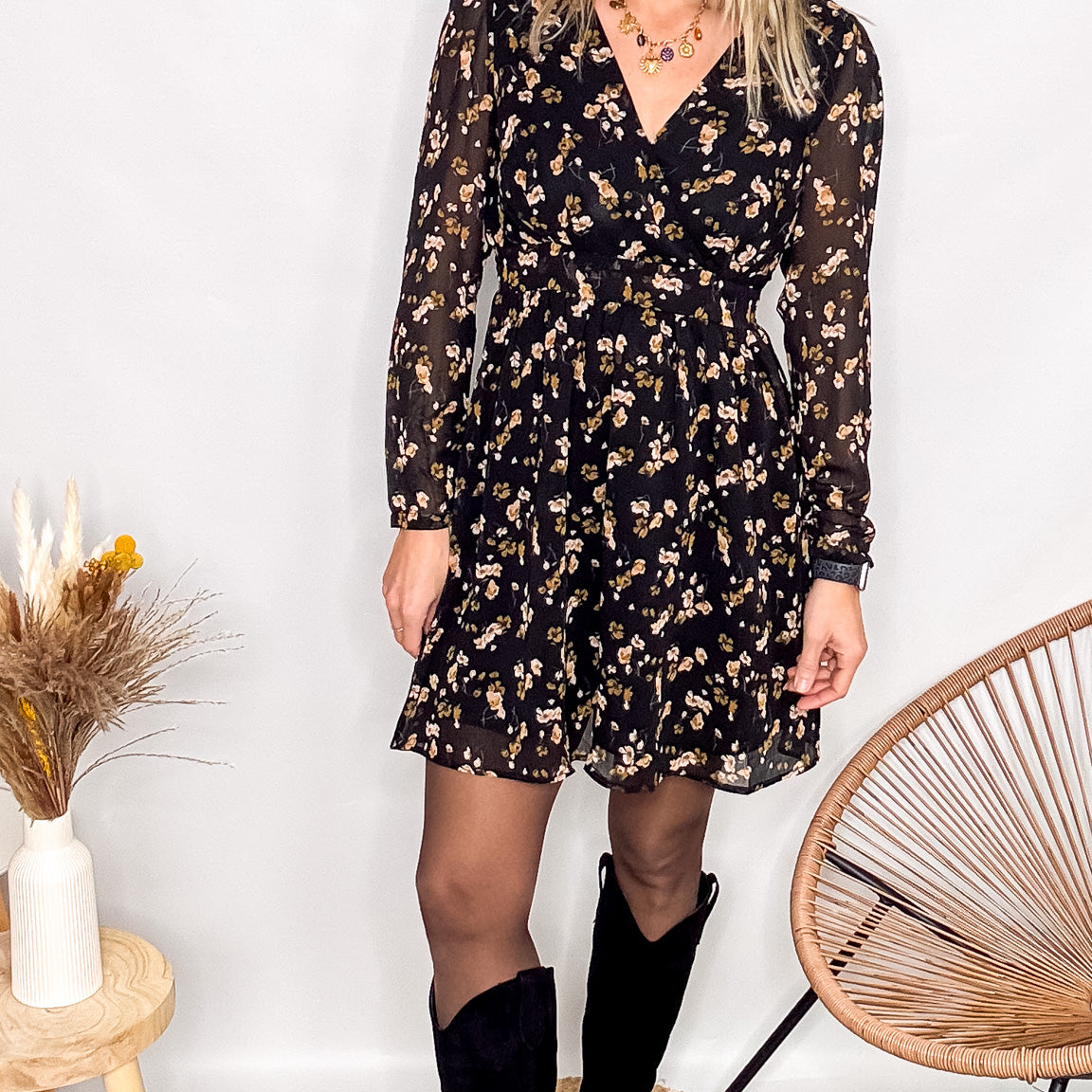 Robe noire fleurie 100% polyester, coupe fluide, portée avec des collants et des bottines.