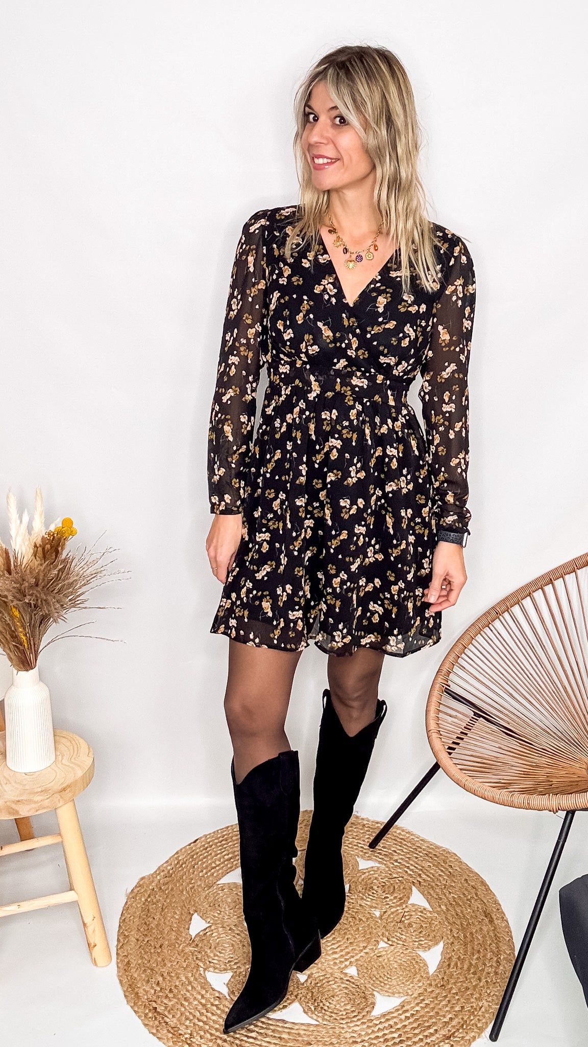 Robe noire fleurie 100% polyester, coupe fluide, portée avec des collants et des bottines.