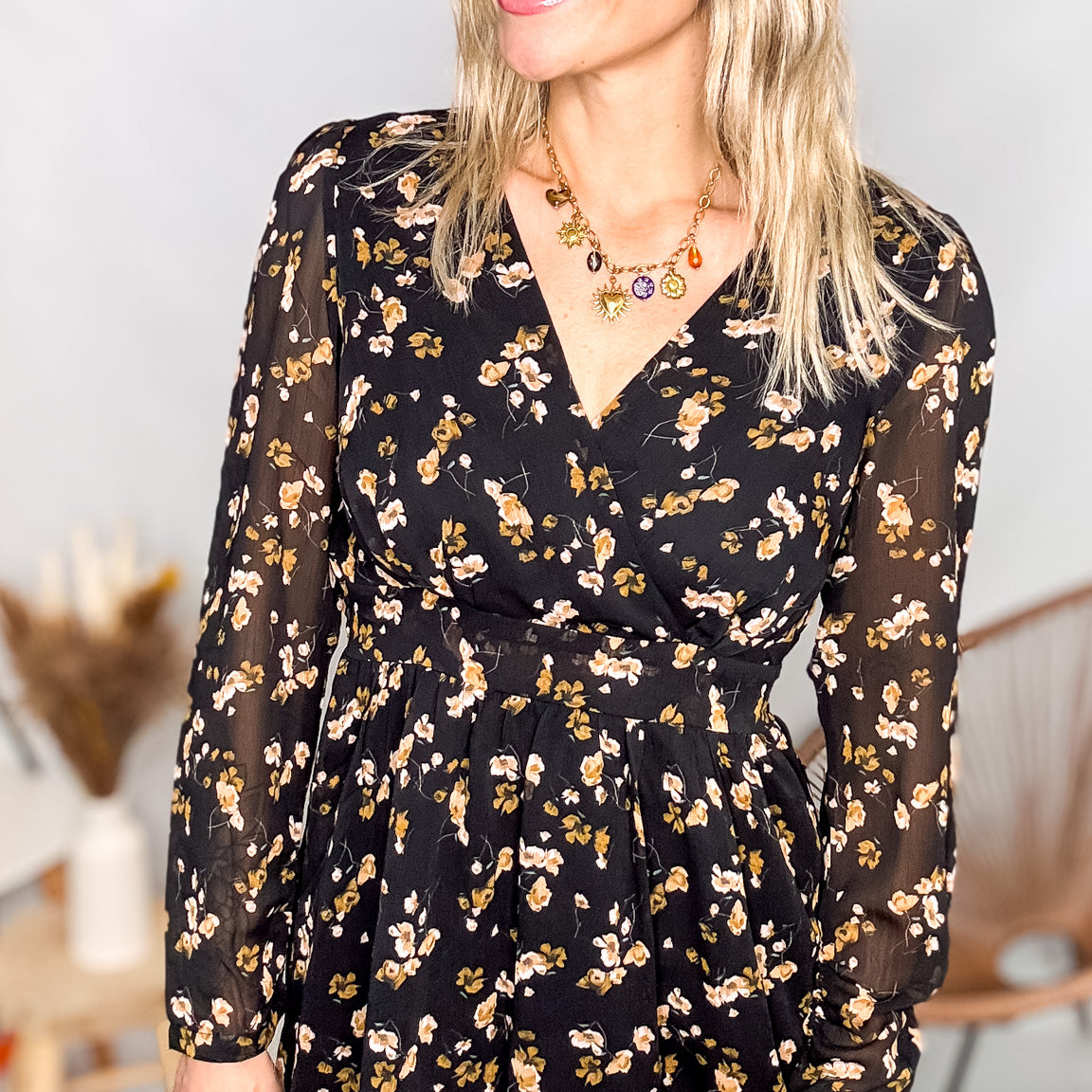 Robe noire fleurie 100% polyester, coupe fluide, portée avec des collants et des bottines.