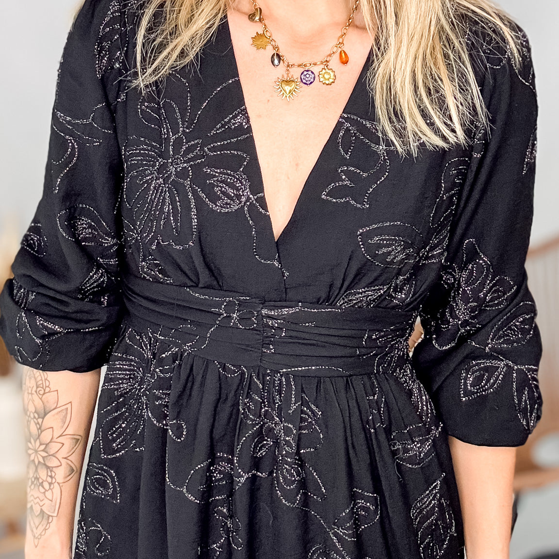 Détail décolleté croisé col V et collier doré sur robe noire brodée