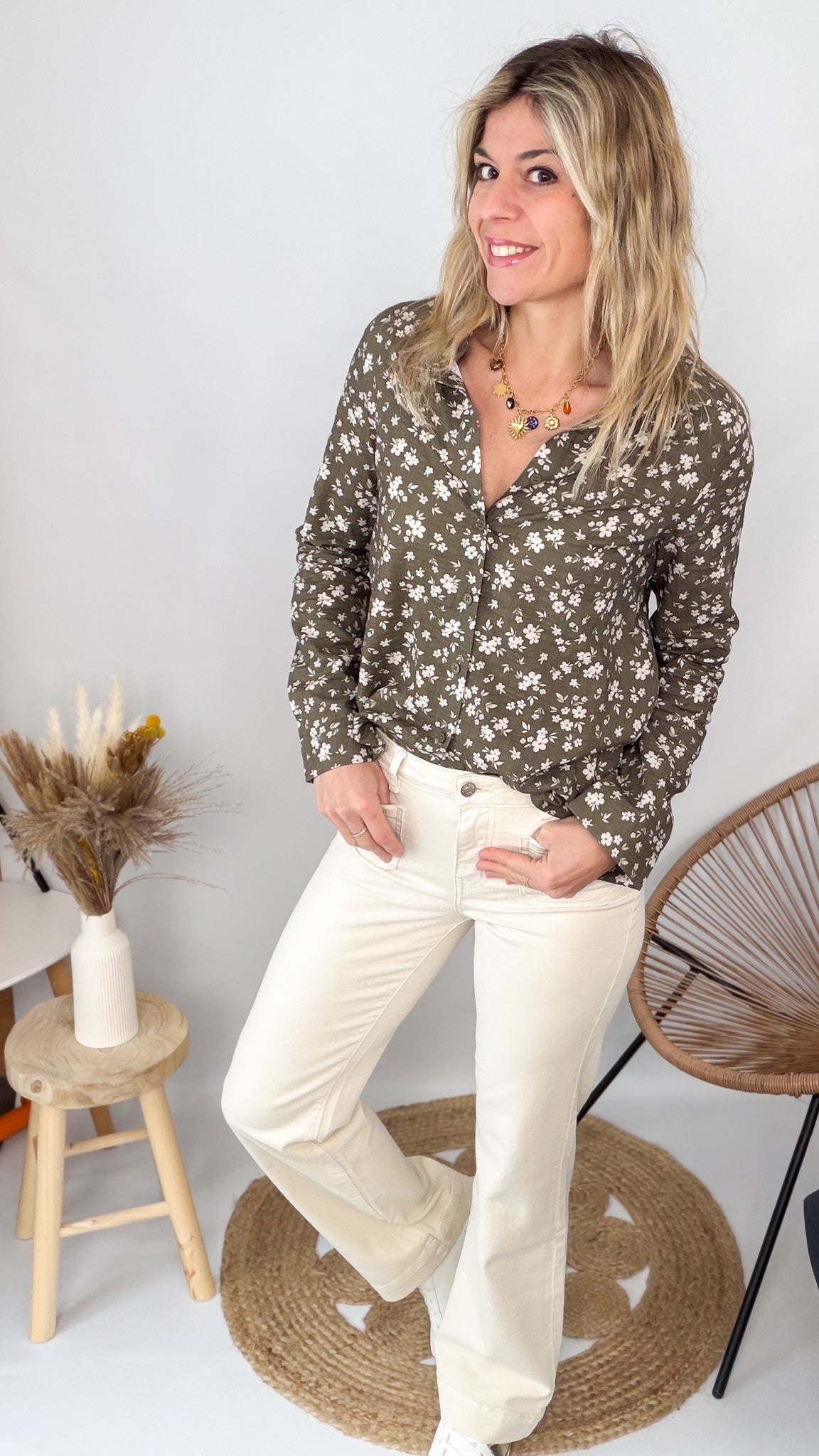 Femme portant une chemise kaki à fleurs blanches et un pantalon blanc - La Boutique de Lydie.