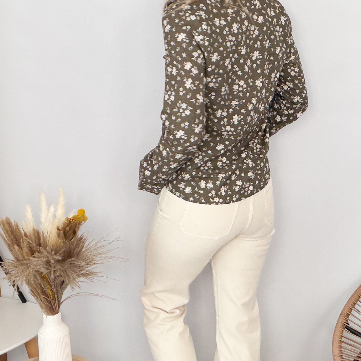 Femme portant une chemise kaki à fleurs blanches et un pantalon blanc - La Boutique de Lydie.