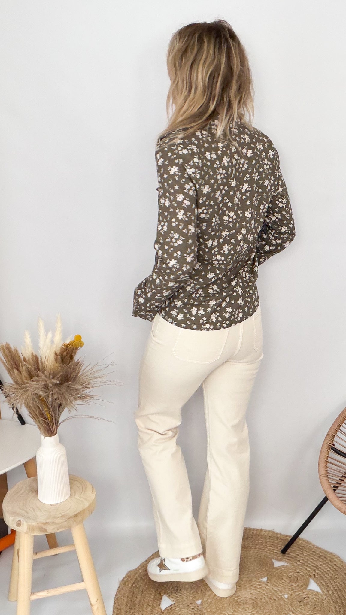 Femme portant une chemise kaki à fleurs blanches et un pantalon blanc - La Boutique de Lydie.