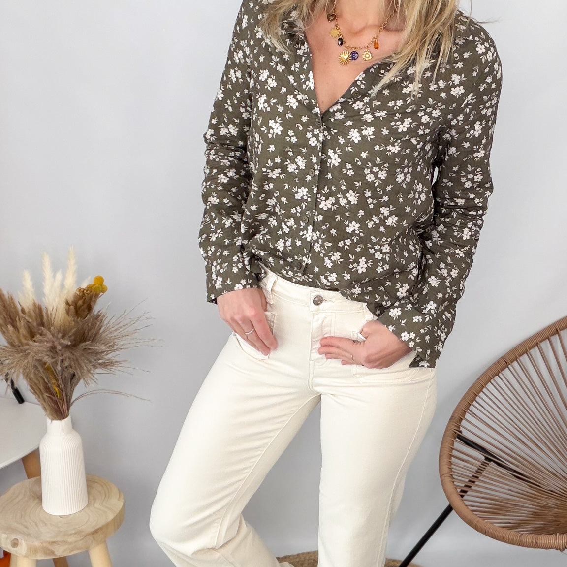Femme portant une chemise kaki à fleurs blanches et un pantalon blanc - La Boutique de Lydie.