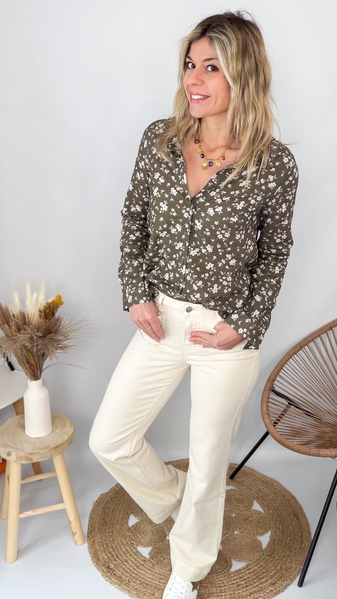 Femme portant une chemise kaki à fleurs blanches et un pantalon blanc - La Boutique de Lydie.