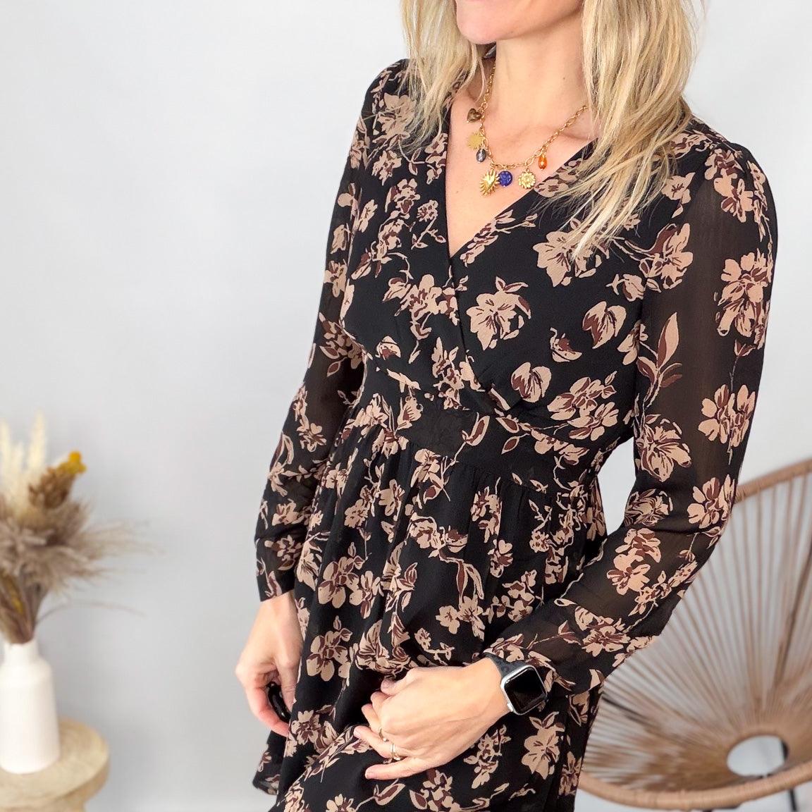 Femme portant une robe noire courte à fleurs avec des bottes noires - Prêt-à-porter La Boutique de Lydie.