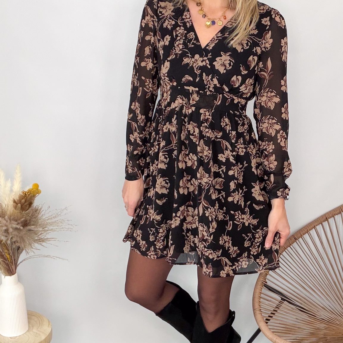 Femme portant une robe noire courte à fleurs avec des bottes noires - Prêt-à-porter La Boutique de Lydie.